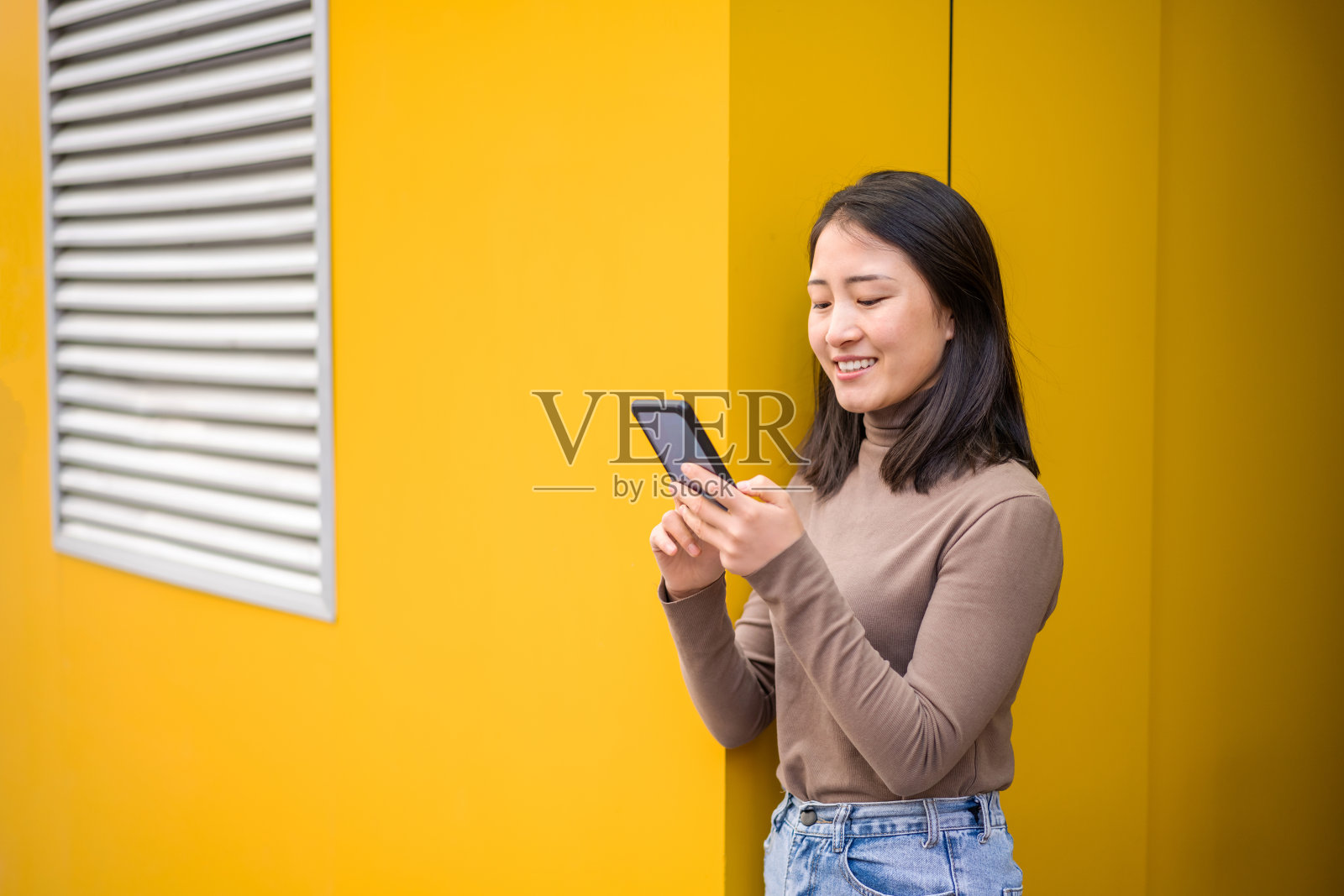 年轻的亚洲女性在城市街道上使用智能手机照片摄影图片
