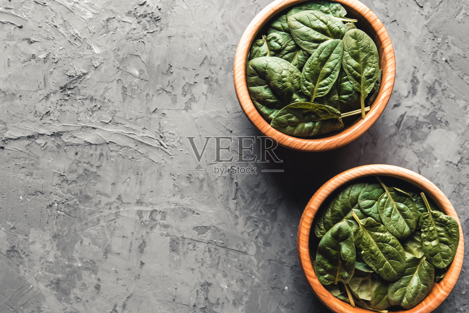 在灰色混凝土背景的碗里，菠菜嫩叶。清洁饮食，排毒照片摄影图片