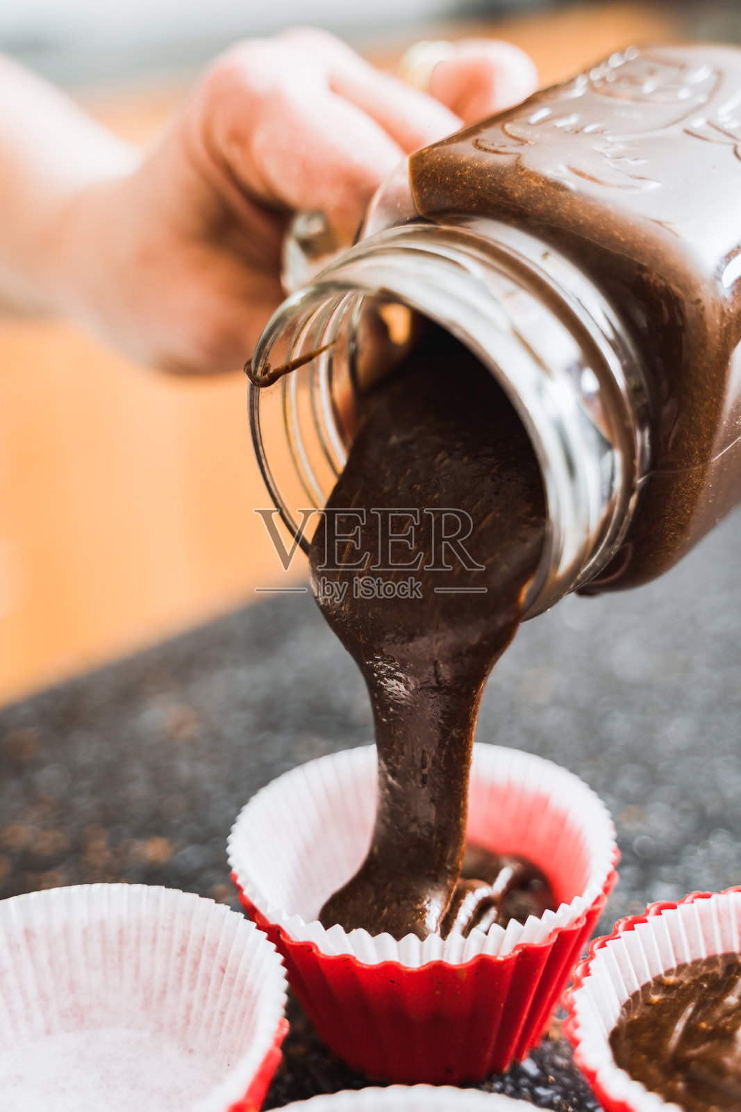 家庭主妇将巧克力面团倒入蛋糕烘焙模具中。照片摄影图片