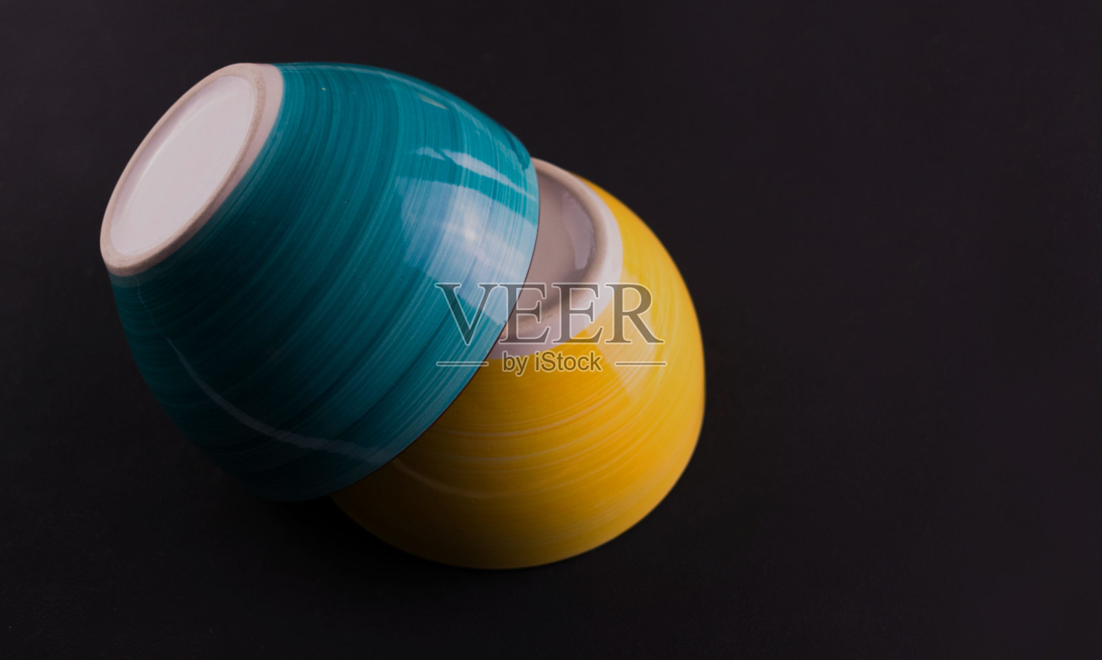 黑色背景上的两个黄色和蓝色的陶瓷碗。副本的空间。照片摄影图片