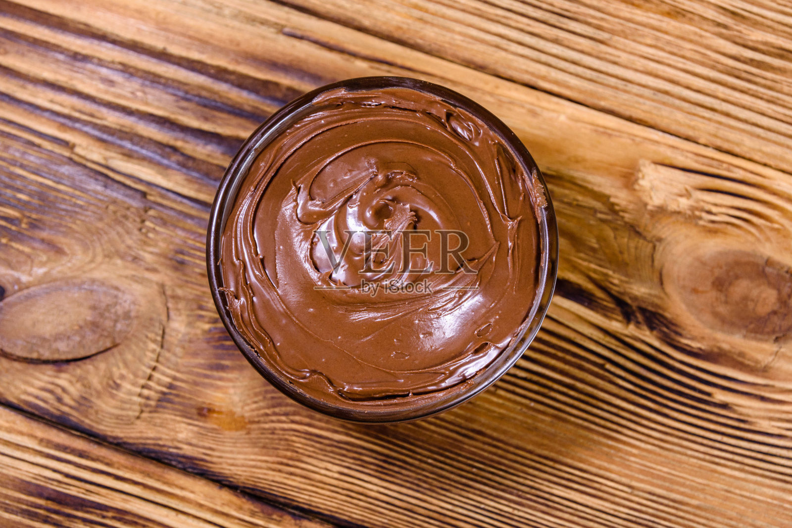 木桌上有一个玻璃碗，上面铺着巧克力。俯视图照片摄影图片