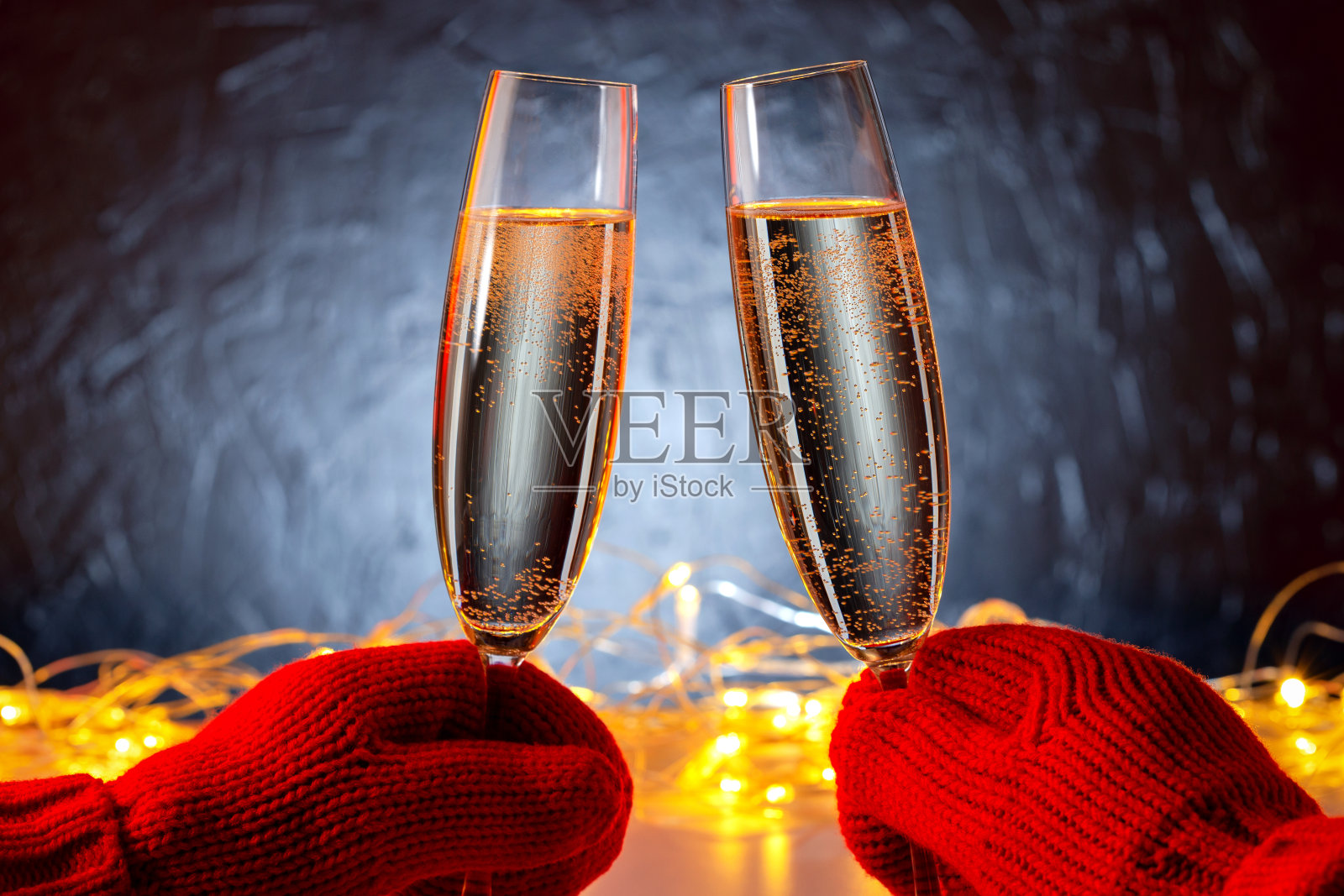 近距离观看的双手穿着暖和的衣服在双手捧着酒杯起泡酒祝贺新年或圣诞节户外。照片摄影图片