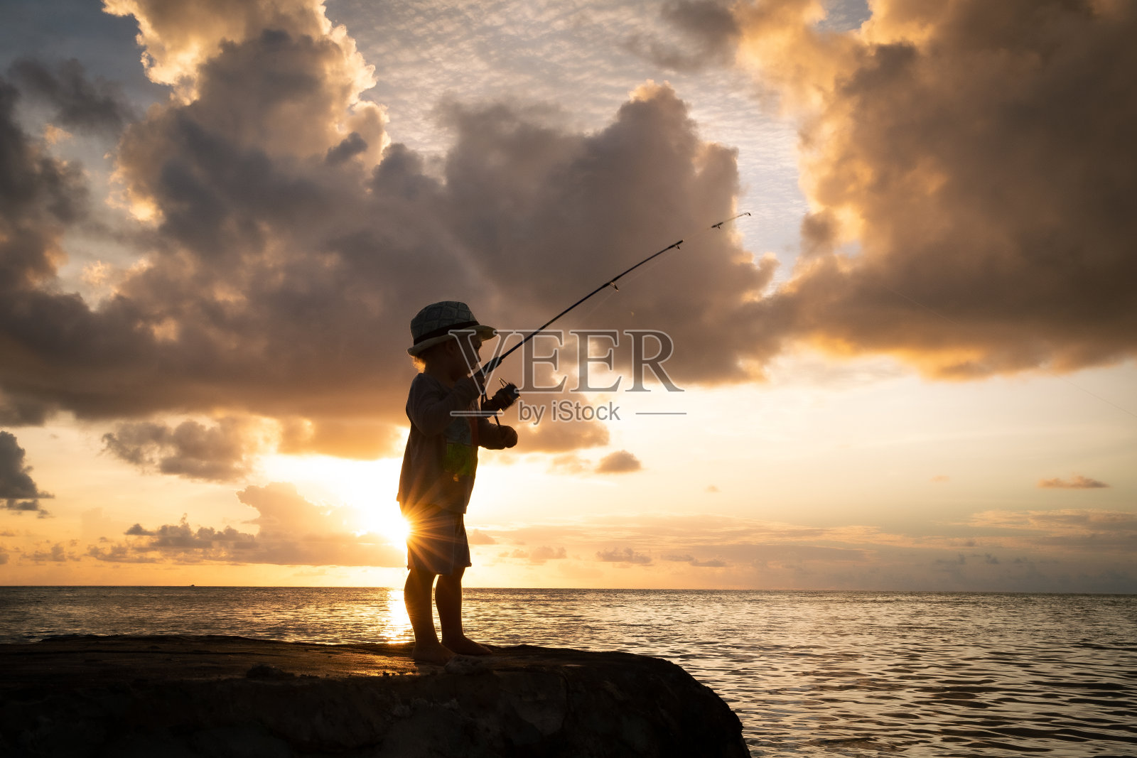 金色云彩在捕鱼的男孩照片摄影图片