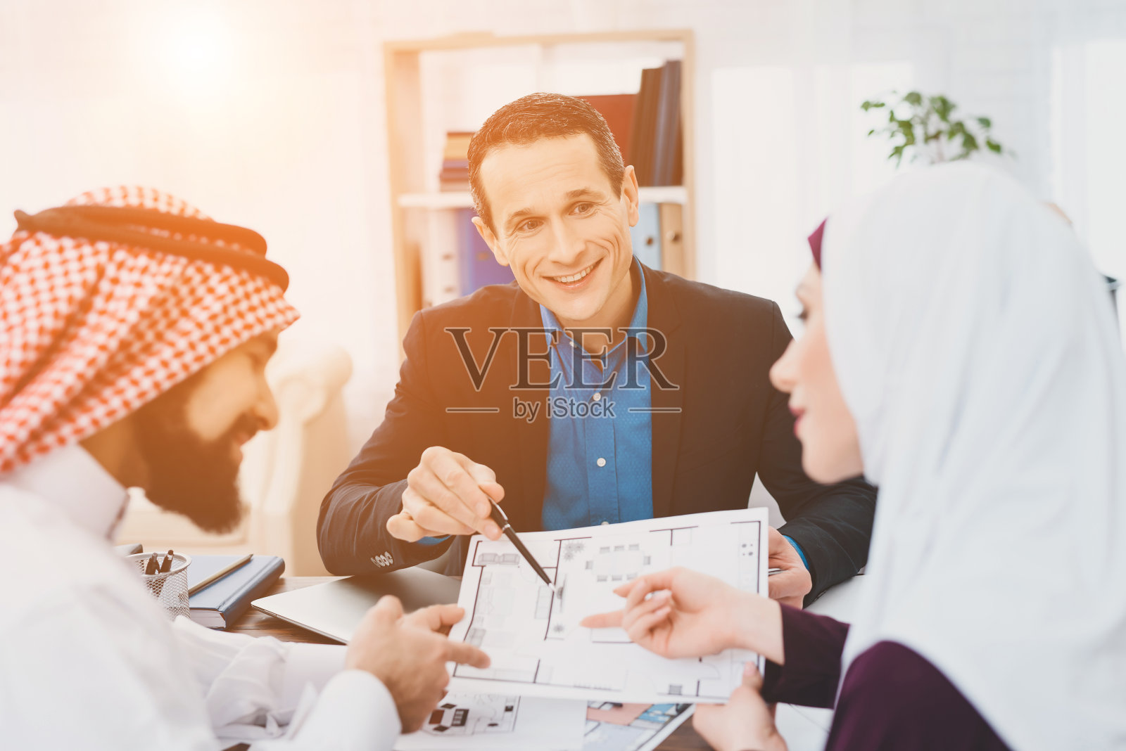 阿拉伯夫妇在房地产经纪人的办公室里认真研究建筑平面图照片摄影图片