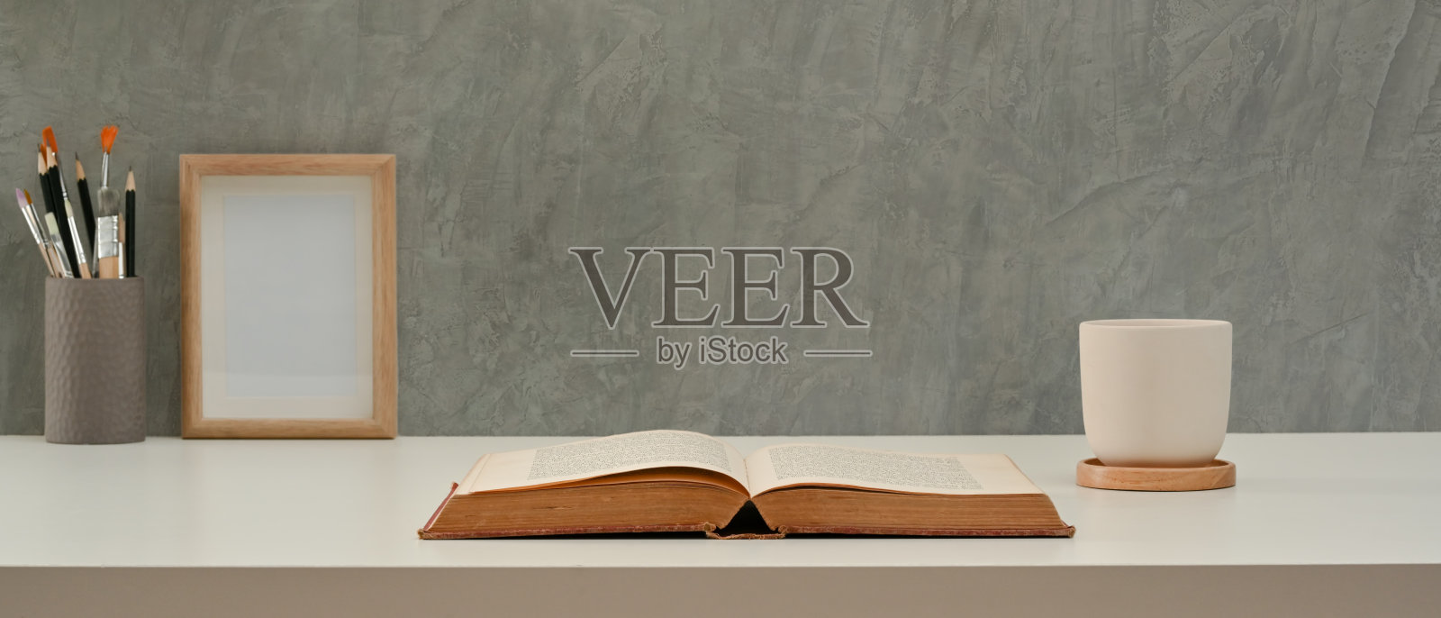 在家庭办公室的书桌，打开的书，杯子，文具和模拟框架照片摄影图片