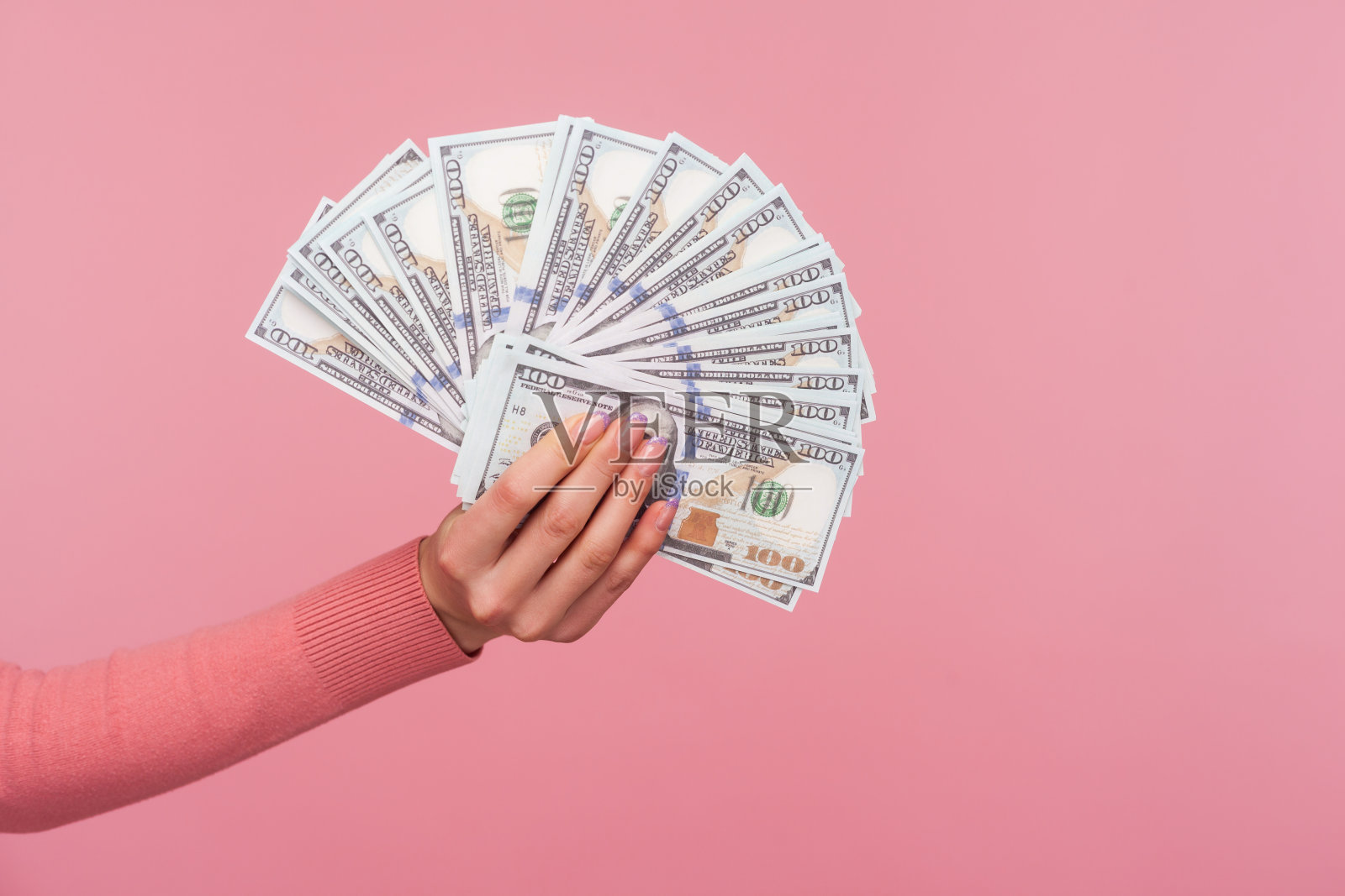 特写侧视图女性手在粉红色毛衣持有和显示美元钞票，大工资，利润照片摄影图片