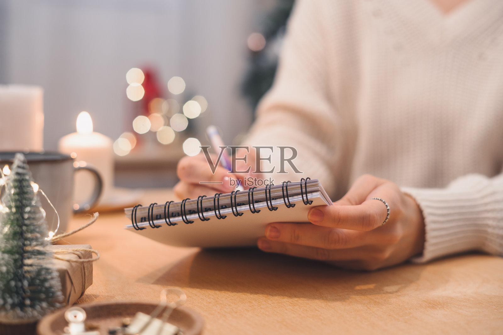 女人手里拿着笔写着圣诞愿望清单、目标。照片摄影图片