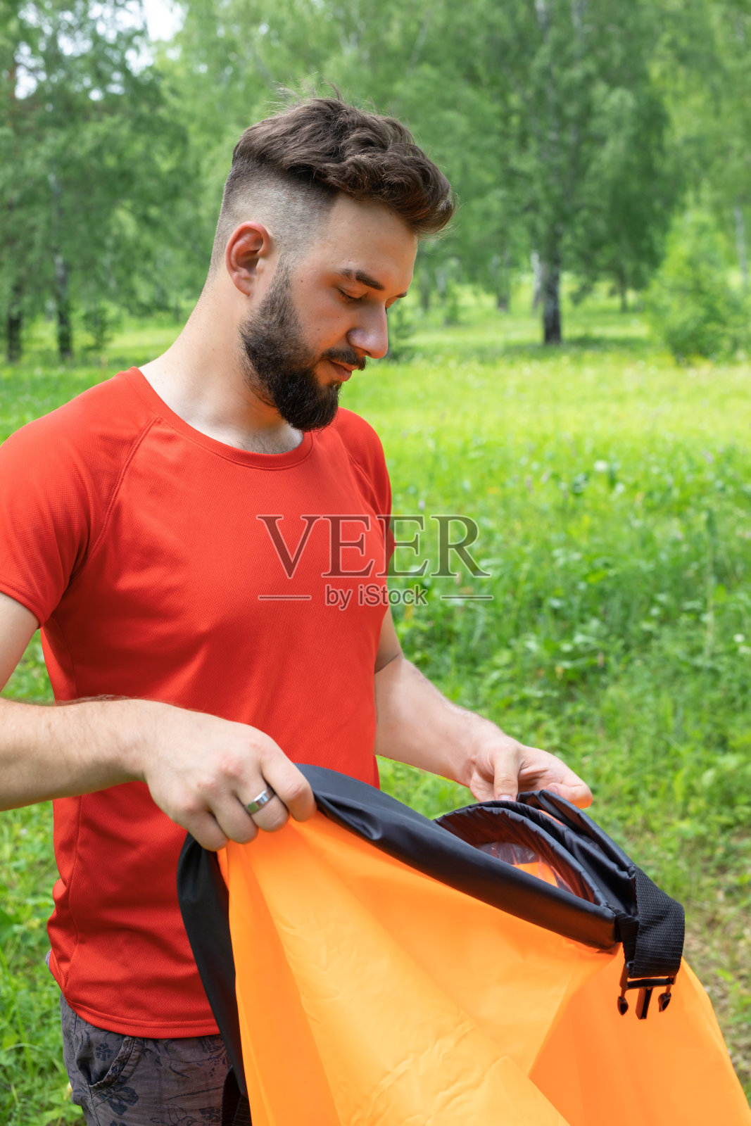年轻人把空气吸进空气沙发里，拉姆扎克。男子试图给空气躺椅充气。在绿色的夏日背景下照片摄影图片