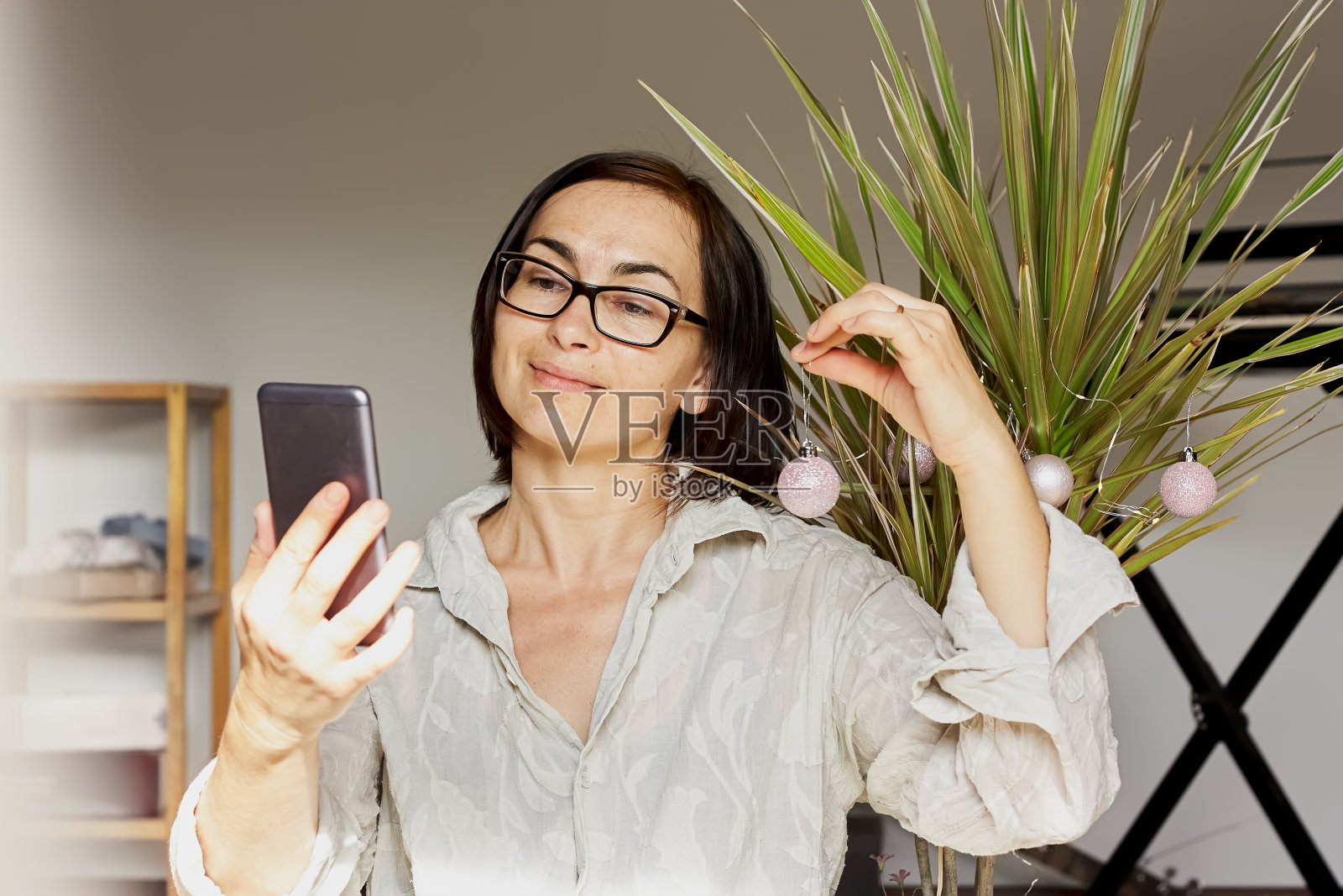 褐发女人把棕榈树装饰成圣诞树，还会自拍。另类的，环保的寒假。照片摄影图片