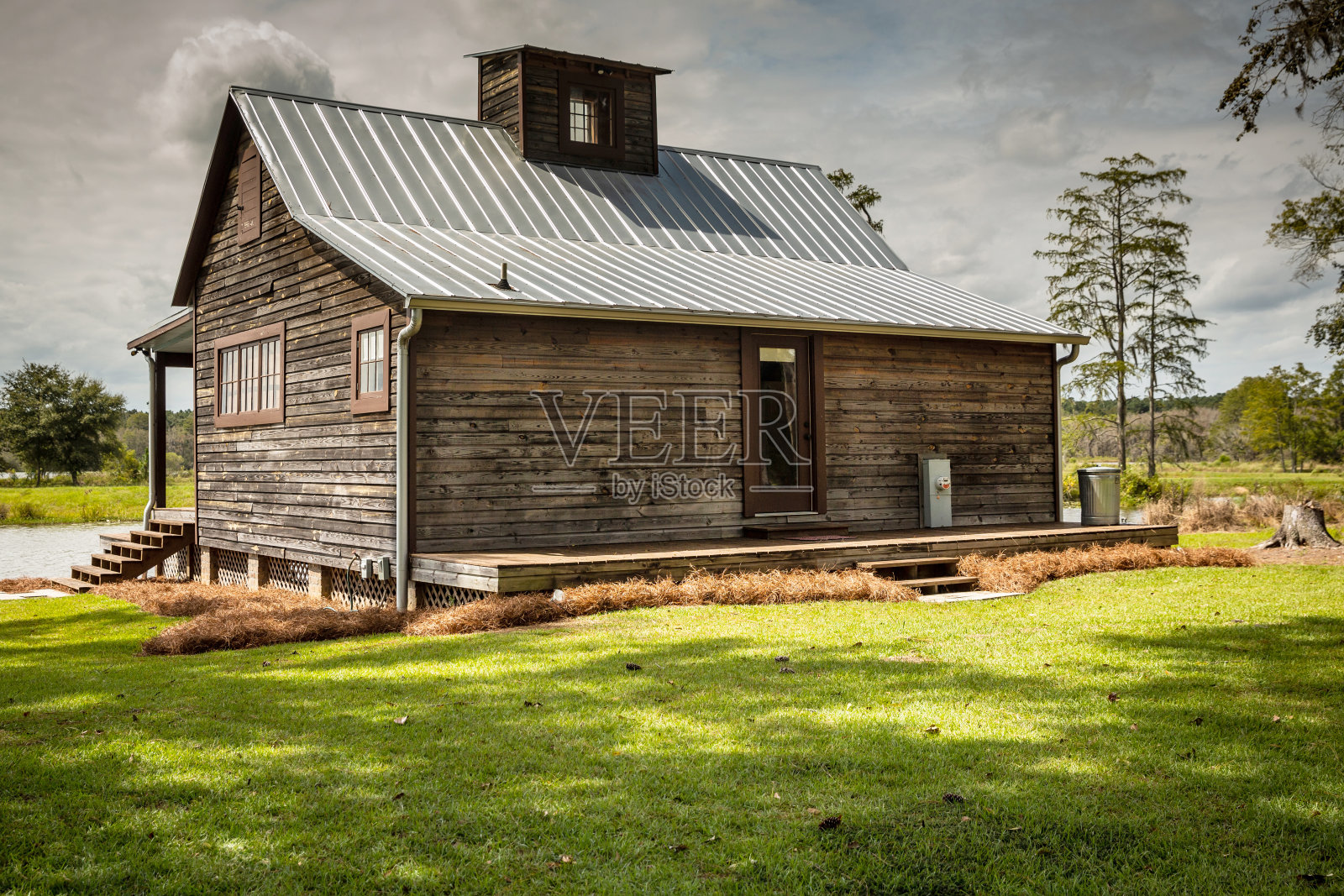 一个用于钓鱼和打猎的乡村的木制野营房子的后视图。房子坐落在一个大池塘上照片摄影图片