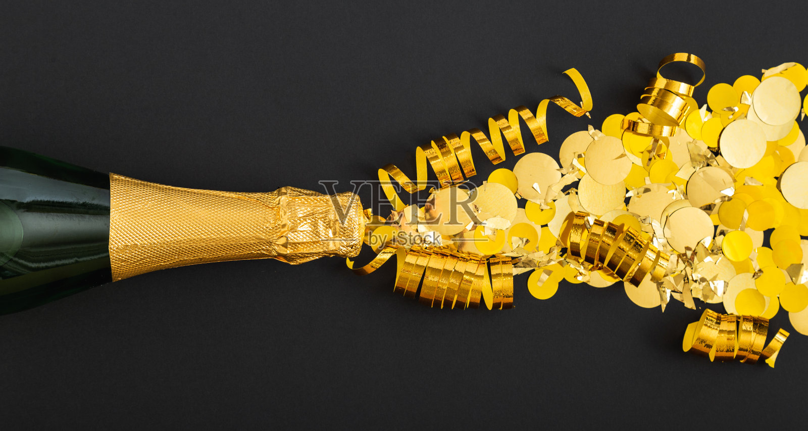 金色的香槟酒在黑色的背景上散发出金色的光芒。香槟闪光爆炸。平躺着新年前夕庆祝活动的黑暗背景。长网络横幅照片摄影图片