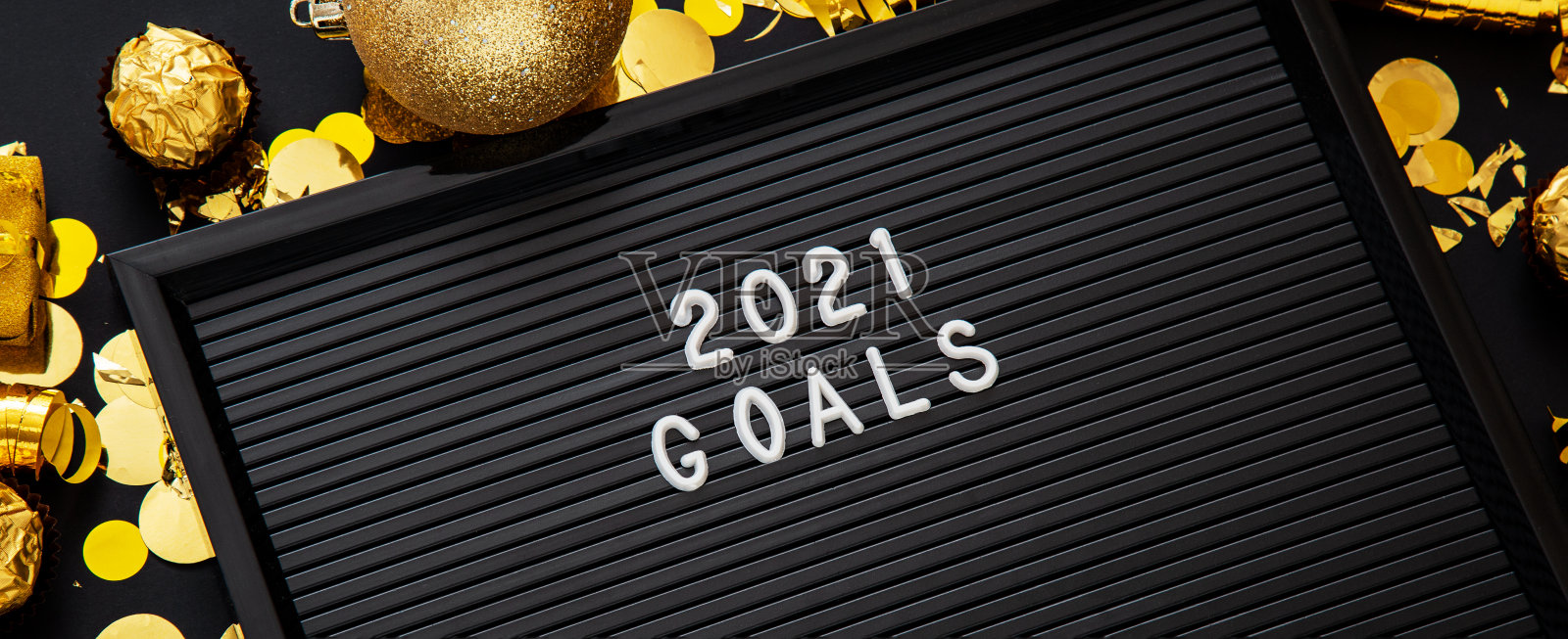 在圣诞装饰的黑色字母板上写着“2021目标”的文字，彩纸球。2021年的目标、决心、动机清单或愿望清单。长网络横幅。照片摄影图片