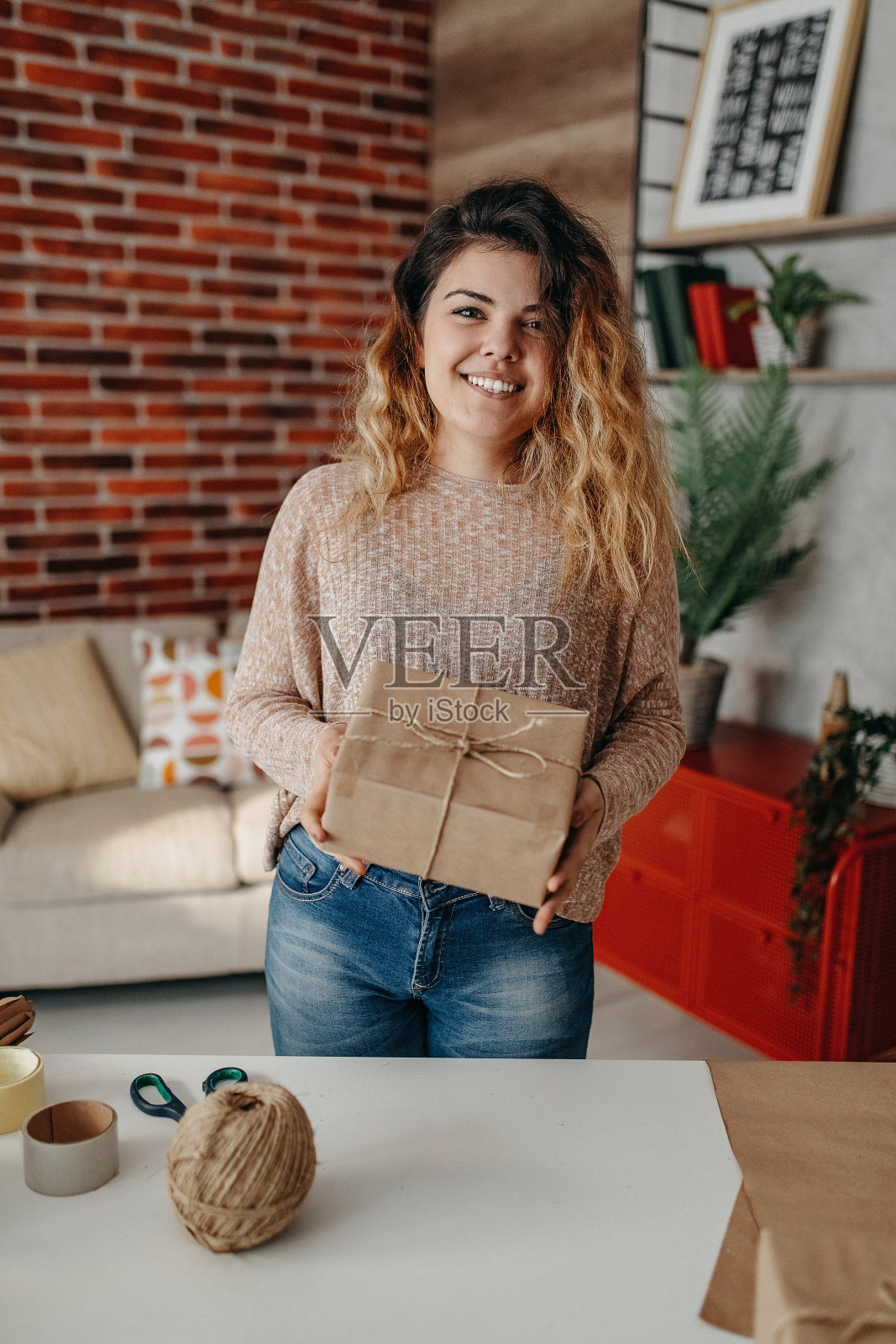 女性手里拿着用彩带包好的牛皮纸小盒子照片摄影图片