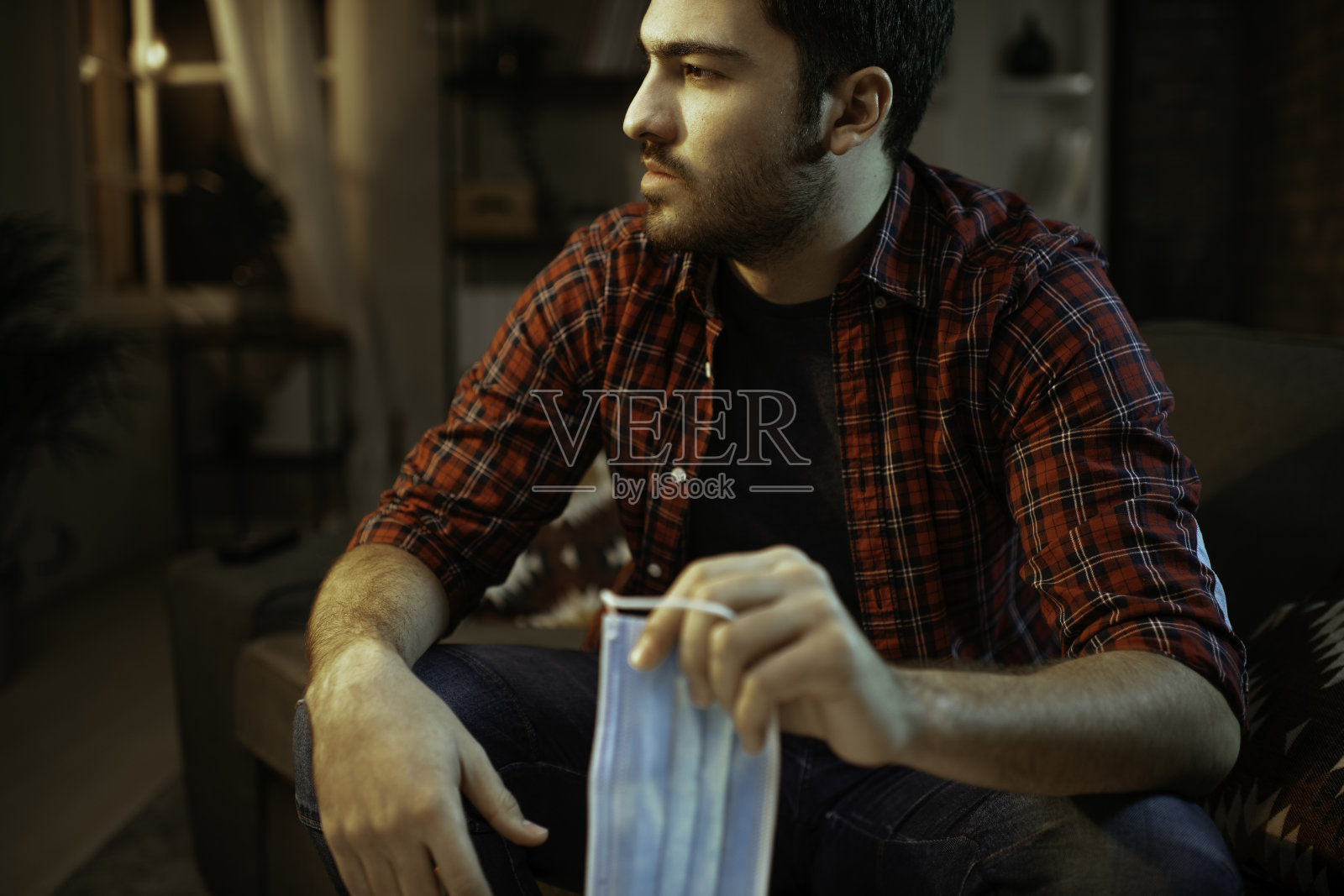 在家戴着防护口罩的悲伤男人照片摄影图片