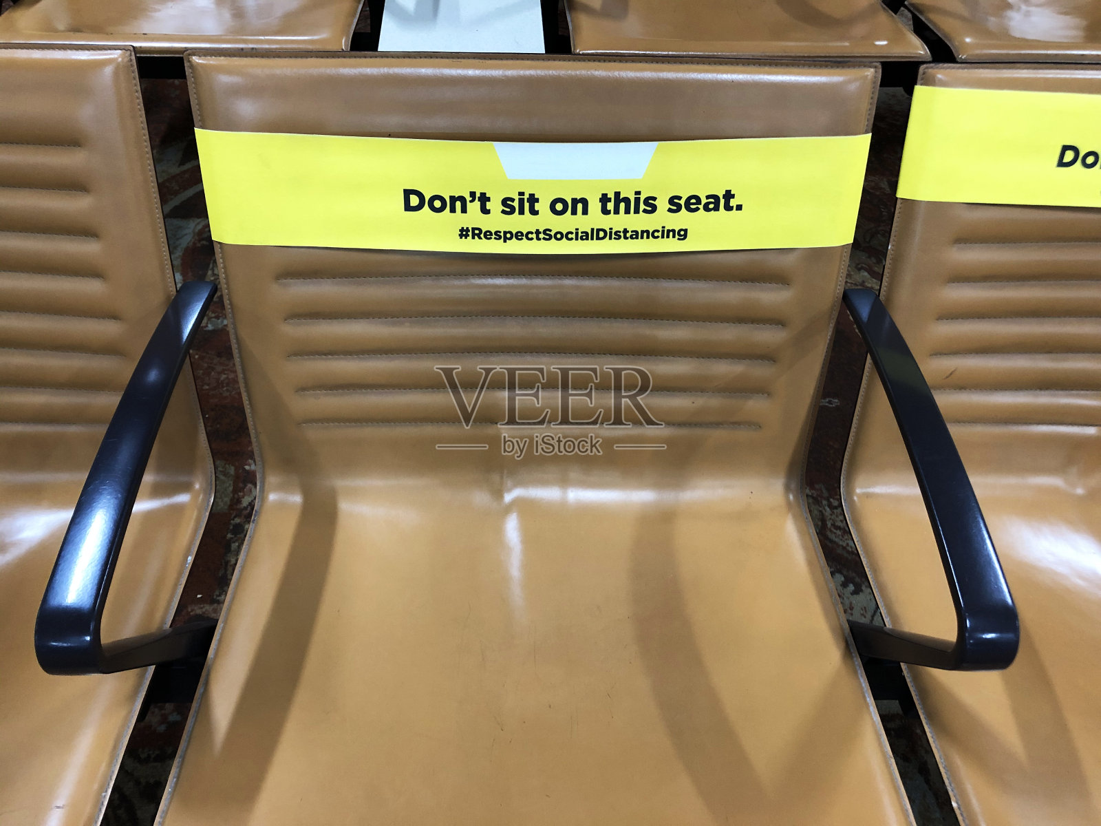 机场候机楼空座位的特写图像，执行新冠肺炎社交距离规定的座位上的标签保持2米距离，新冠肺炎安全照片摄影图片