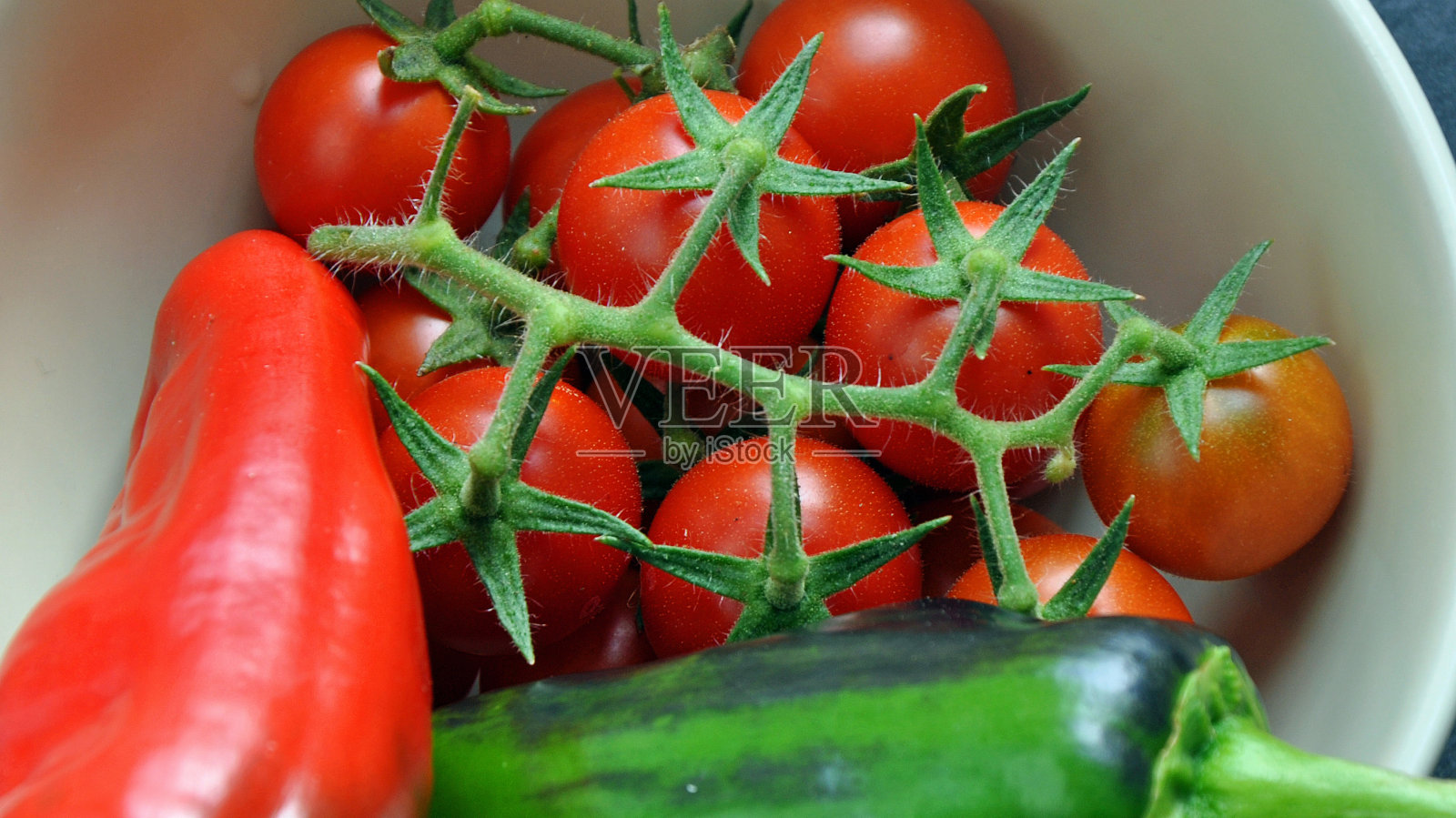 葡萄藤上的圣女果和两个甜柿子放在碗里照片摄影图片