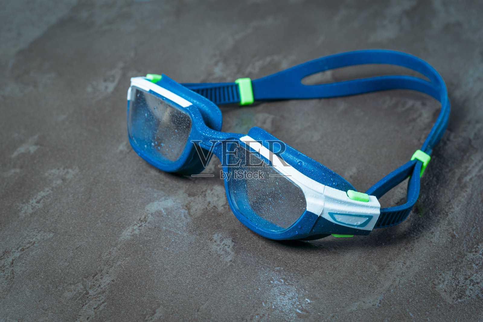 在石头背景上水滴中的男子游泳眼镜。照片摄影图片