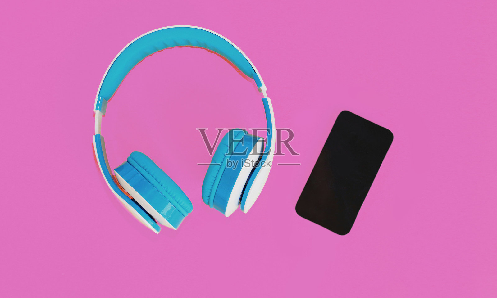 近距离蓝色耳机和智能手机在彩色的粉红色背景照片摄影图片