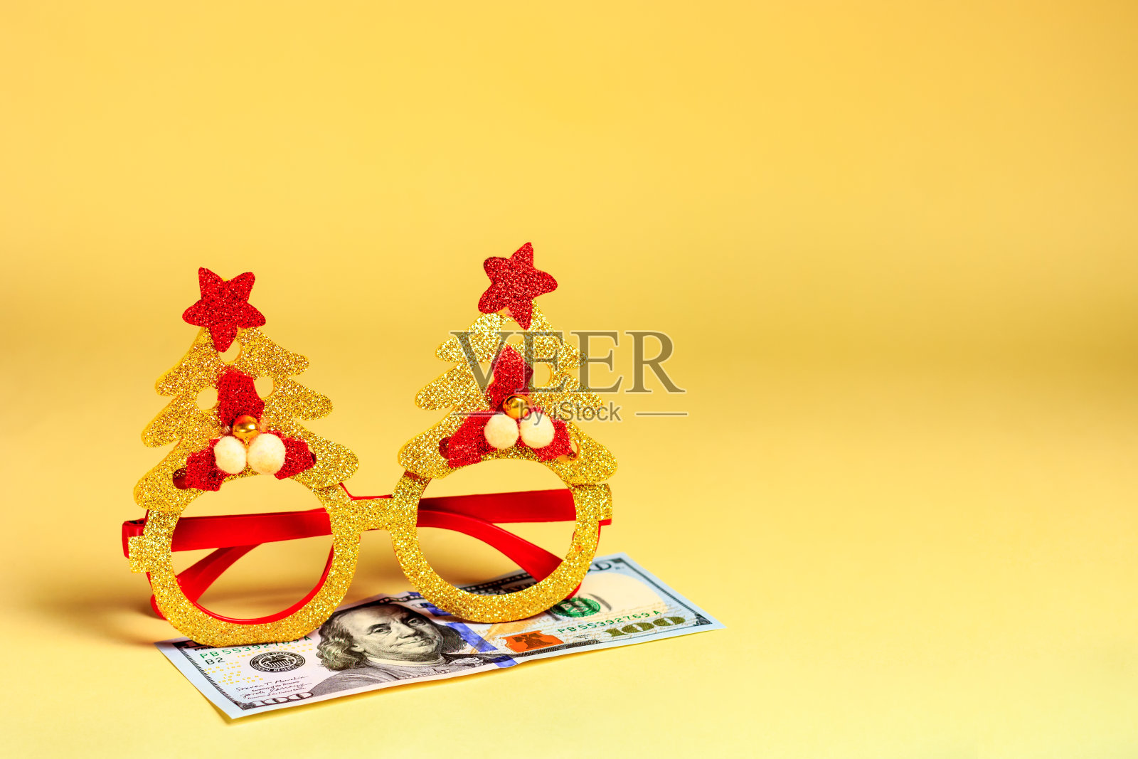 新年、圣诞节假面舞会的眼镜和钞票、美元——躺在黄色的背景上。对捐赠和礼物的敌意预算照片摄影图片