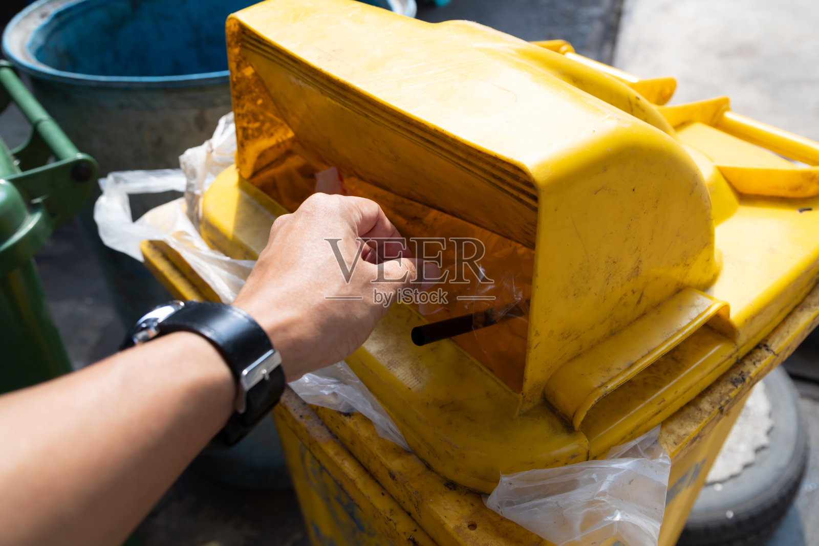 那个人把垃圾扔进肮脏的黄色垃圾里照片摄影图片