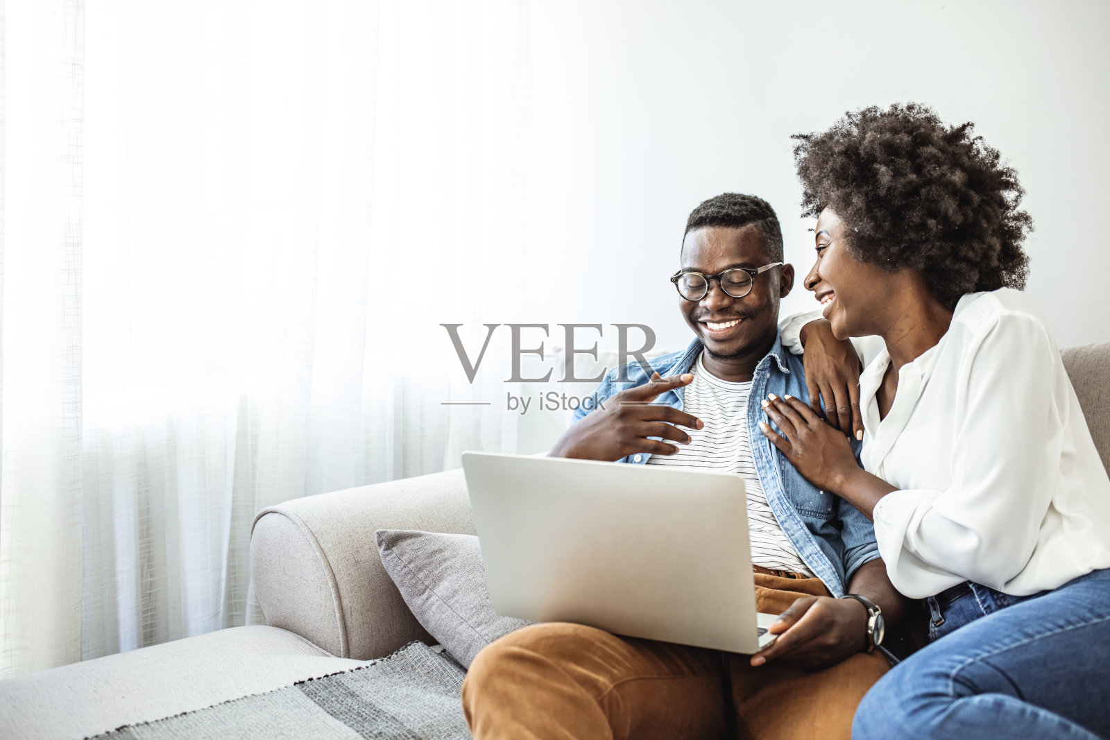 这是一对年轻夫妇在家里沙发上使用笔记本电脑的照片。照片摄影图片