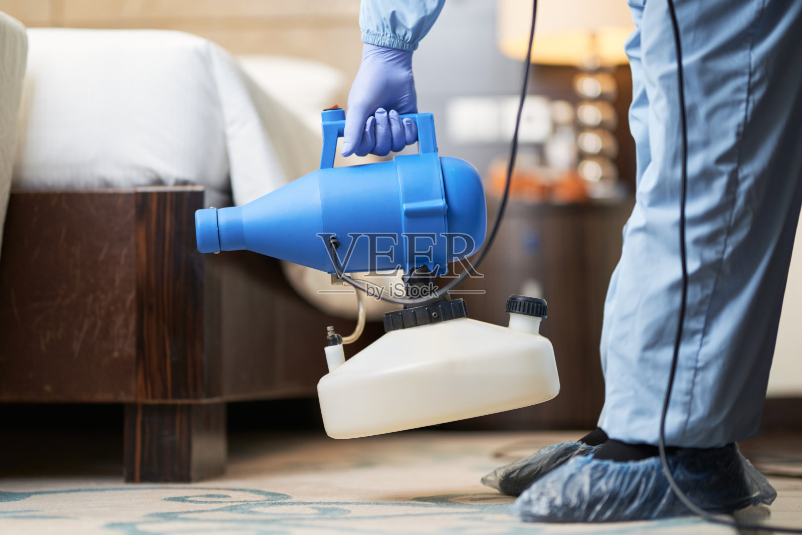 工作人员在冠状病毒防护服消毒室使用喷雾器照片摄影图片