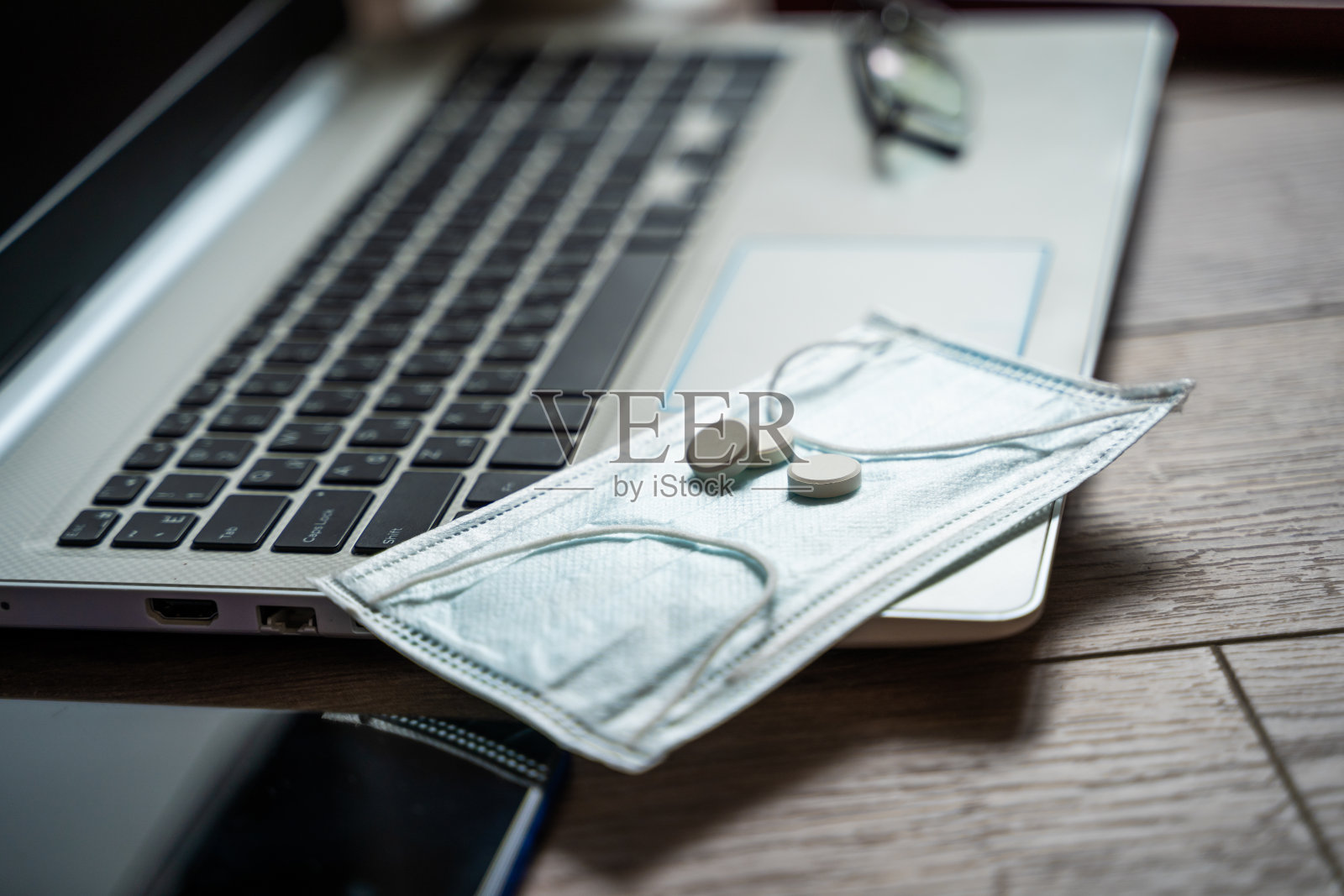 疫情期间远程工作的概念。桌上放着笔记本电脑，卫生用品照片摄影图片