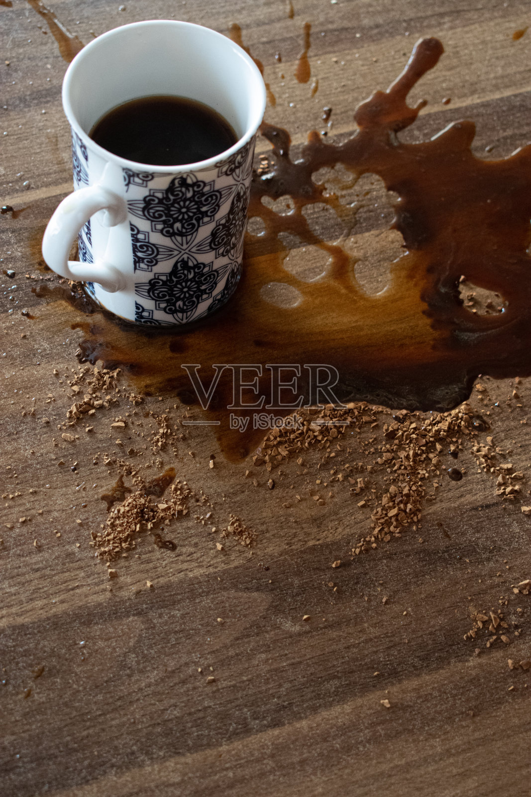 咖啡从杯子里洒出来，咖啡洒在桌子上照片摄影图片