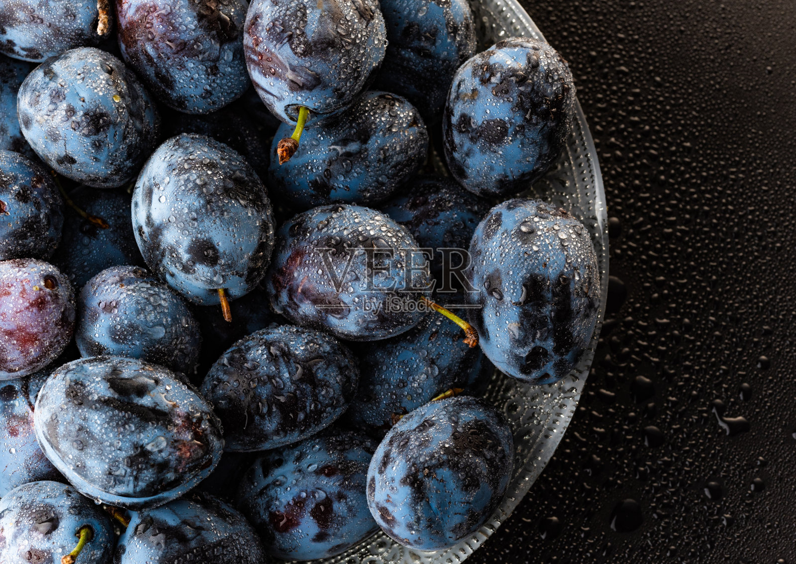 湿漉漉的熟透的李子上滴着水滴，特写照片摄影图片