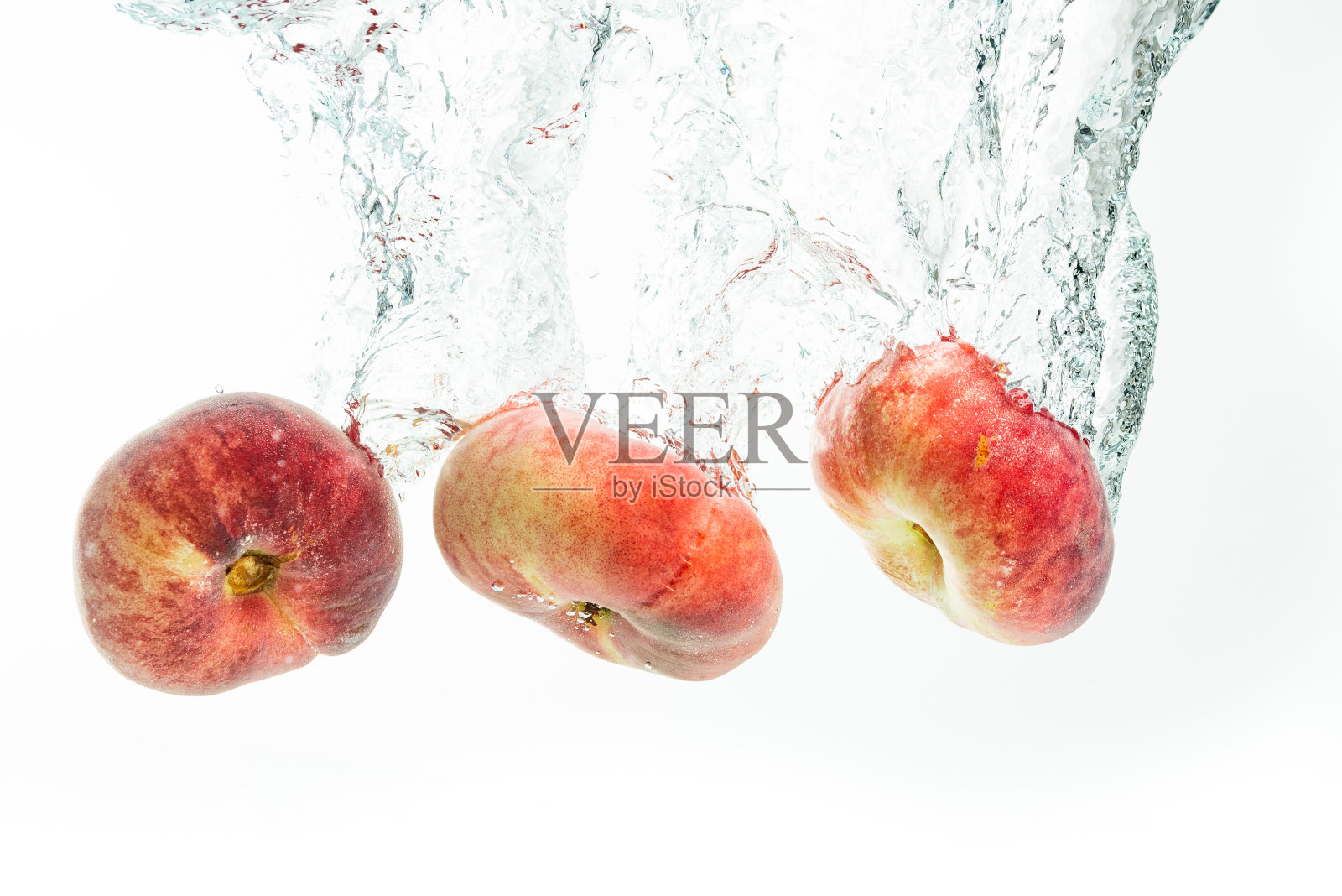 一堆甜甜圈桃子孤立在白色，溅到水里。照片摄影图片