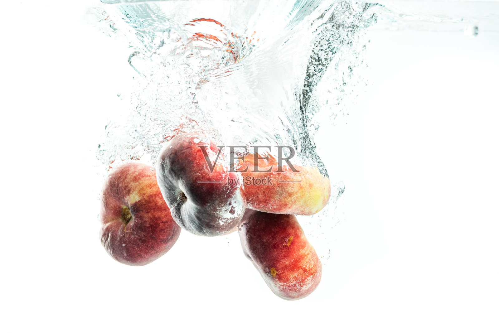 一堆甜甜圈桃子孤立在白色，溅到水里。照片摄影图片