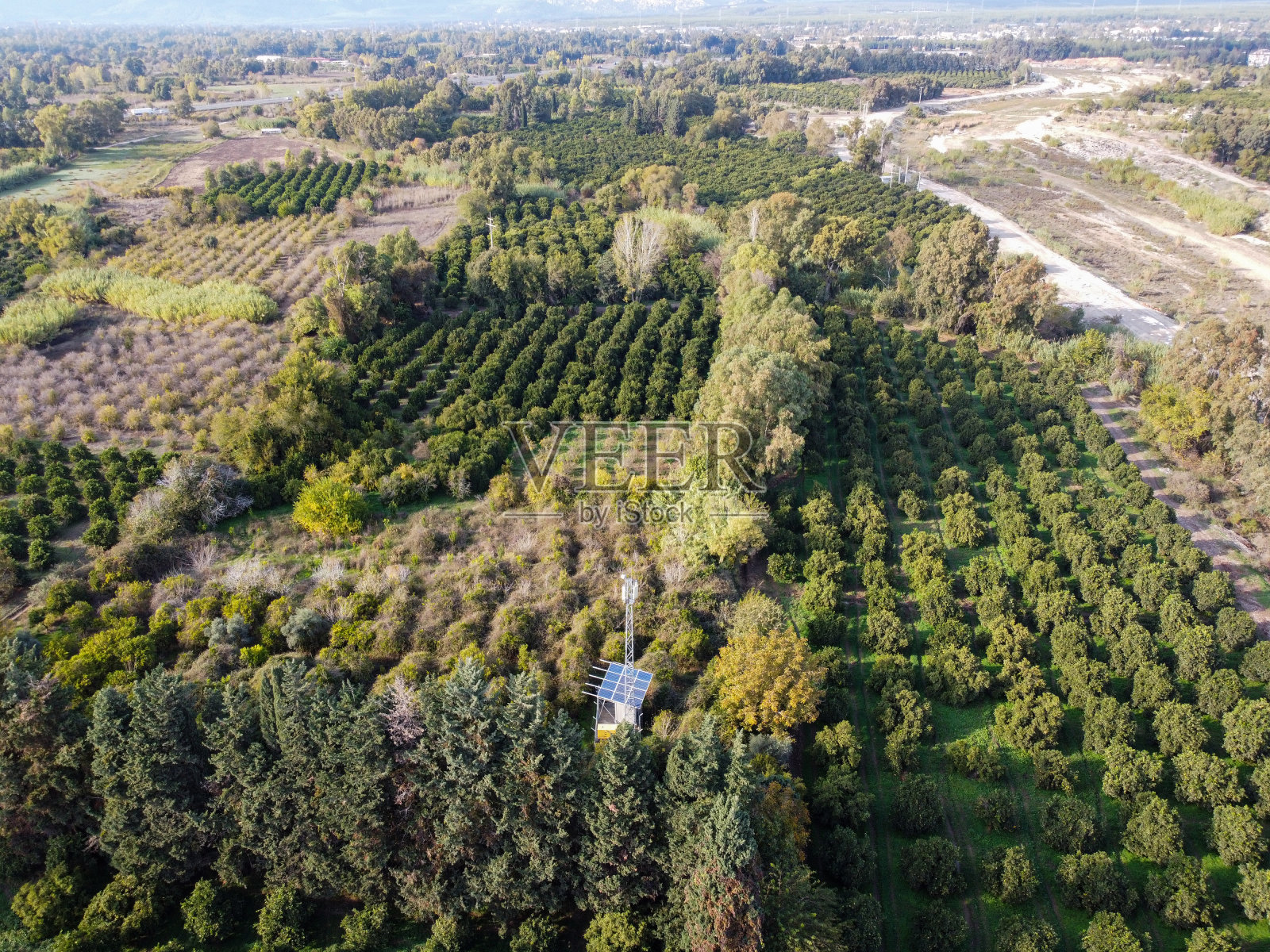 用无人机飞过河床，绿树成荫，车道，城市和山景。照片摄影图片