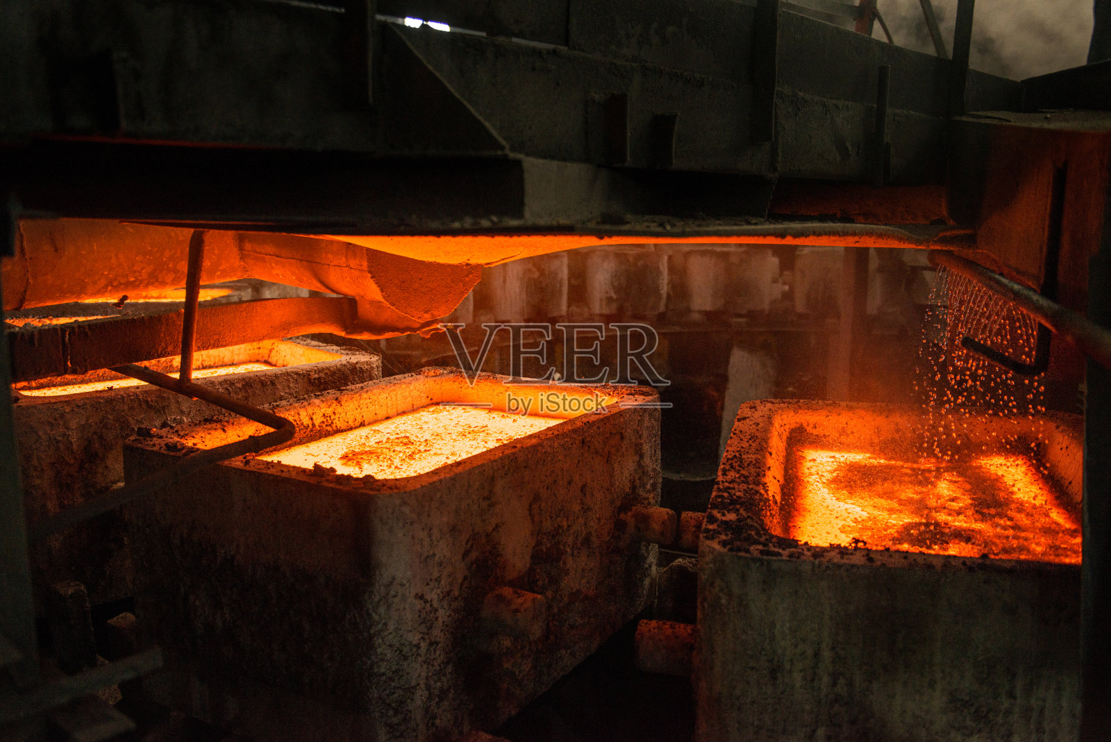 在钢铁厂用转盘机将液态金属放入模具中照片摄影图片