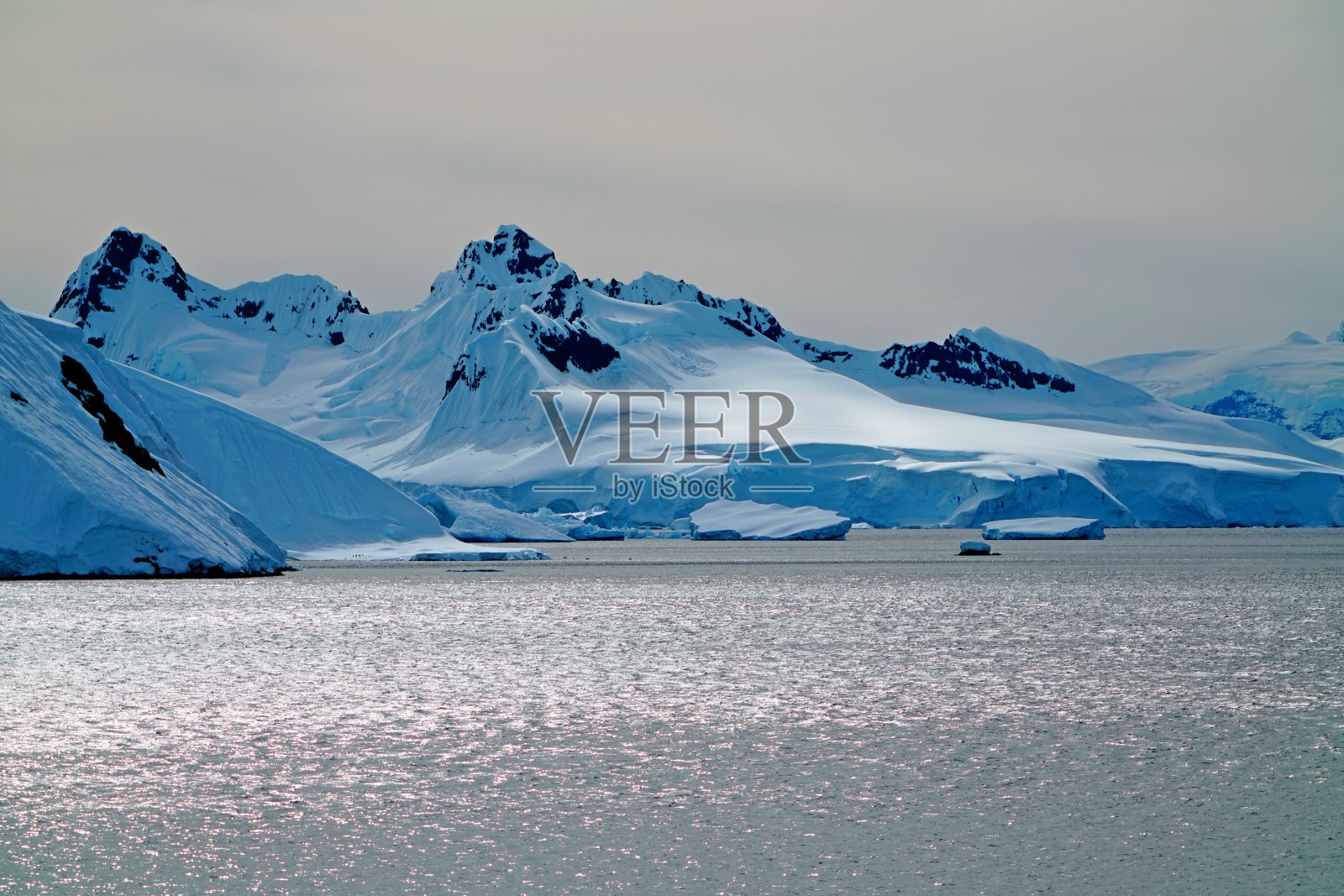 冰山前的海面在阳光下闪闪发光。照片摄影图片