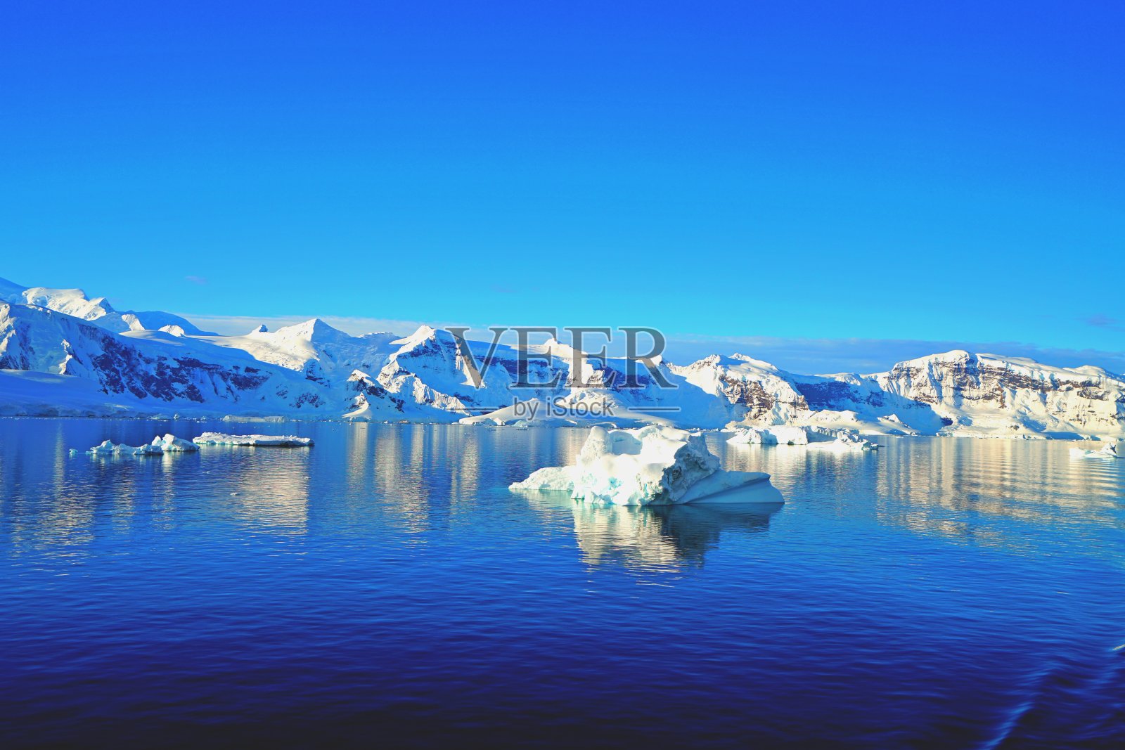海面像一面镜子。它反映了冰山的倒影。蓝天白云也映入了大海。照片摄影图片