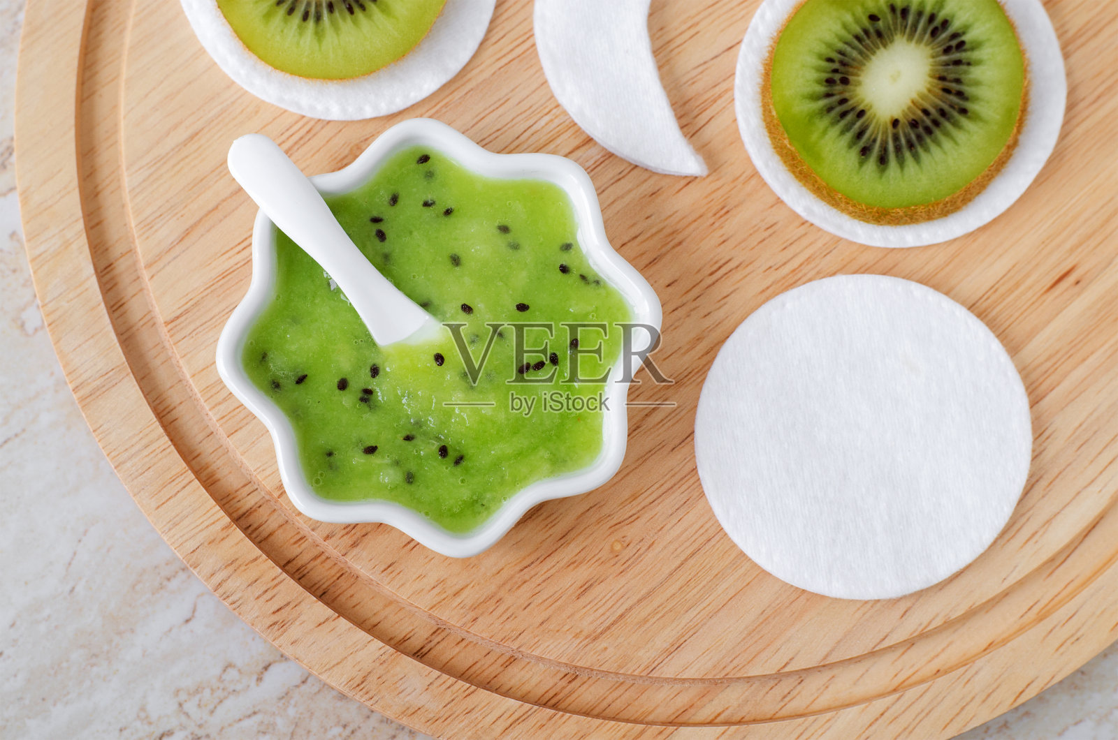 新鲜的猕猴桃泥在一个小的白色碗和棉花垫。自制面膜、天然美容spa配方。俯视图，复制空间。照片摄影图片