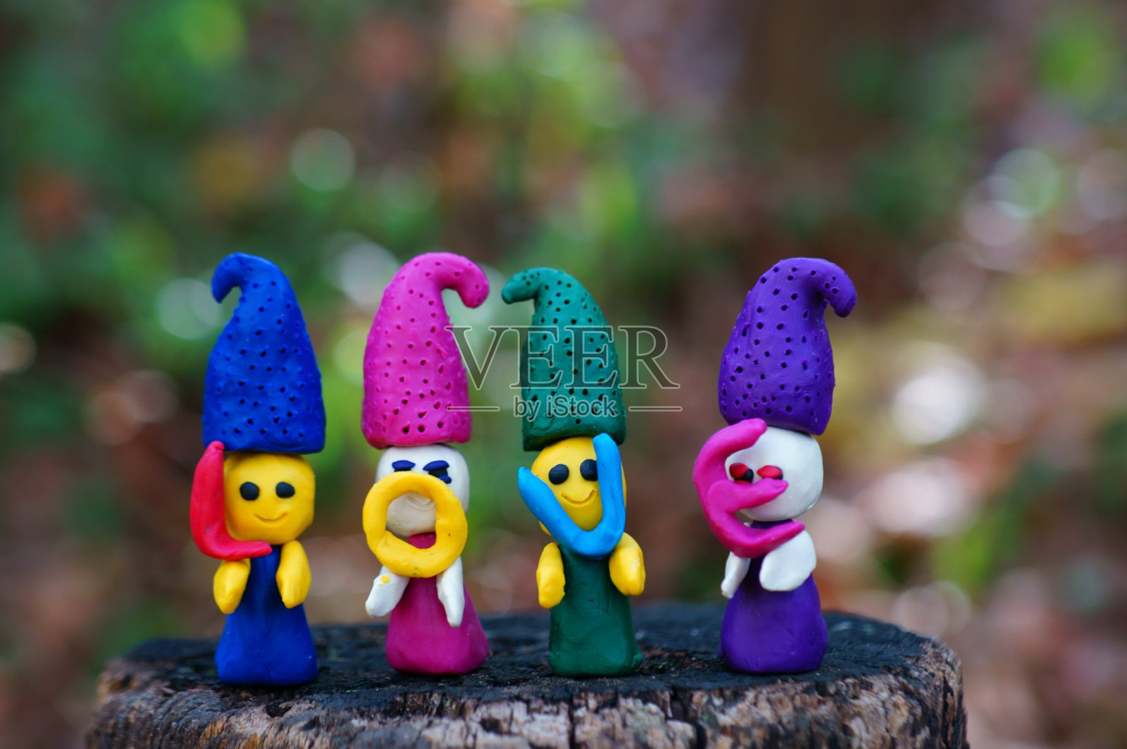 四个用橡皮泥制成的童话故事中的小矮人在森林里的彩色背景上。照片摄影图片