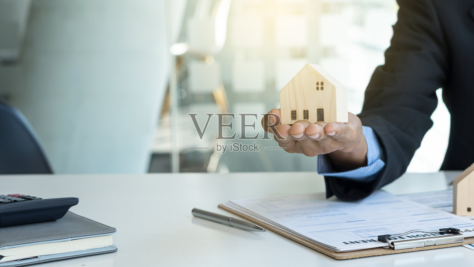 房地产经纪人的手提供一个基于模型的房子。他办公室里的元素照片摄影图片