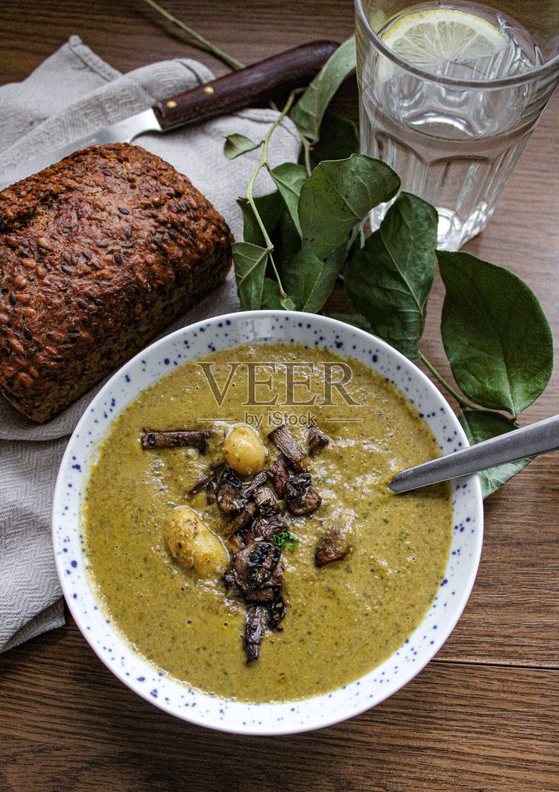 木桌上的碗里放着蘑菇和汤团。照片摄影图片