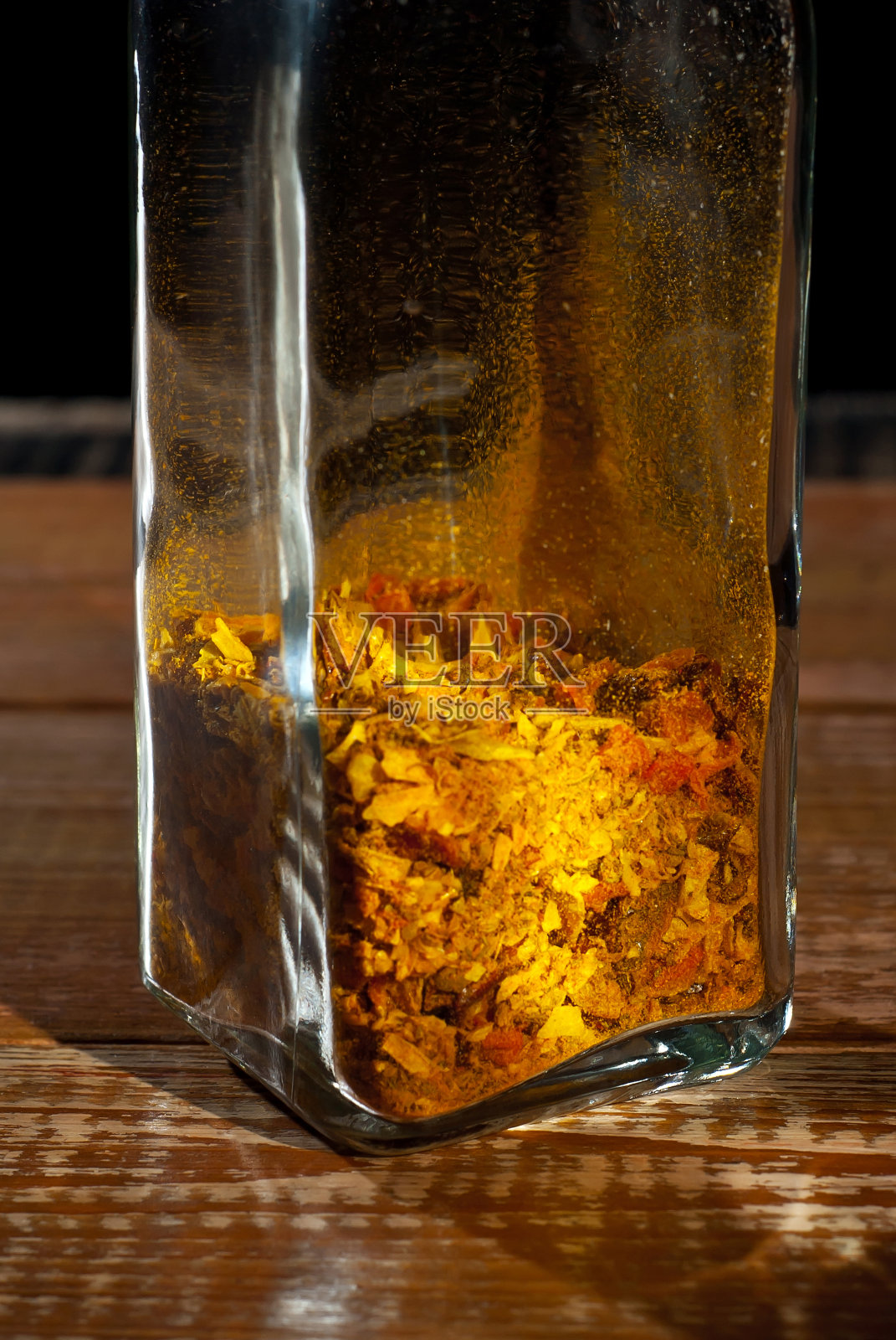 各种香料的混合物在一个玻璃罐中闭合。破旧的木板上放着香料。免费空间和复制空间的文本附近的调味品。作为一种艺术效果来对比戏剧性的光线。照片摄影图片