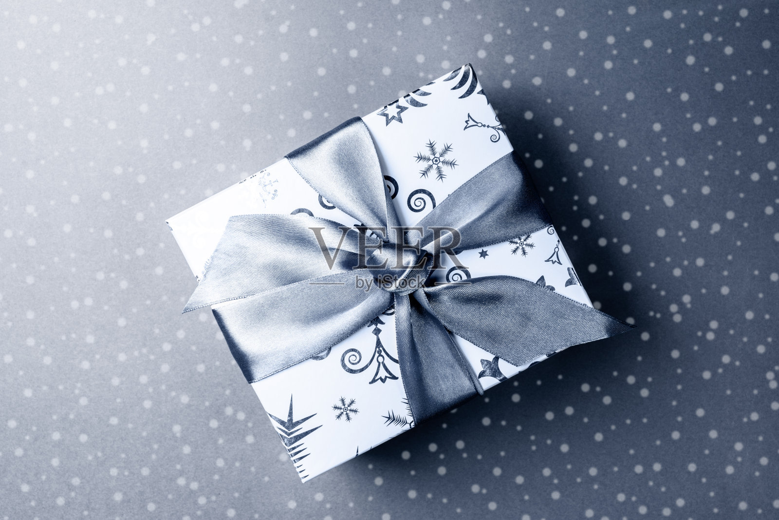 图案的礼盒与DIY蝴蝶结在灰色的背景与绘制的雪。节日喜庆的单色形象。照片摄影图片