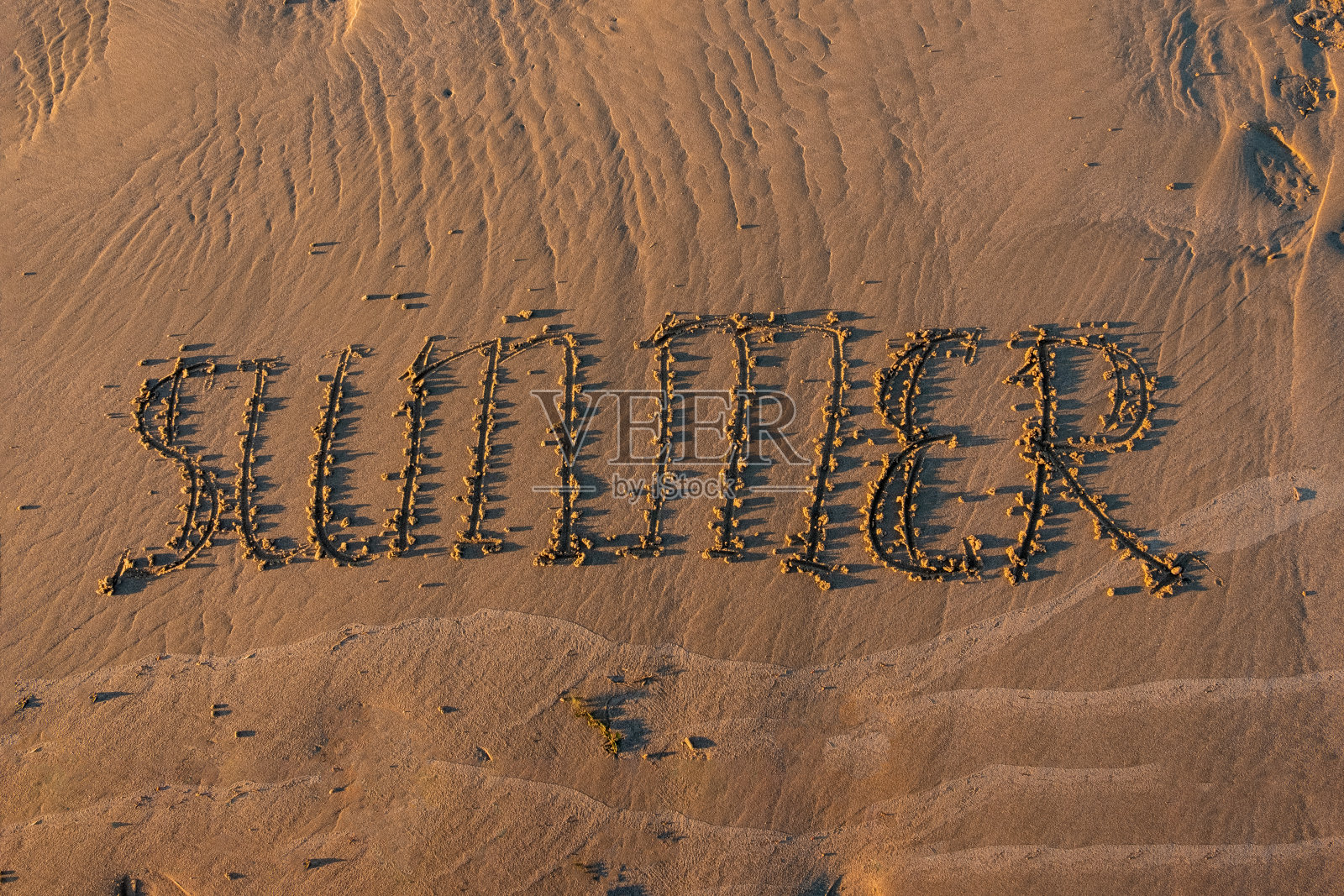 夏天的铭文写在沙滩上。照片摄影图片