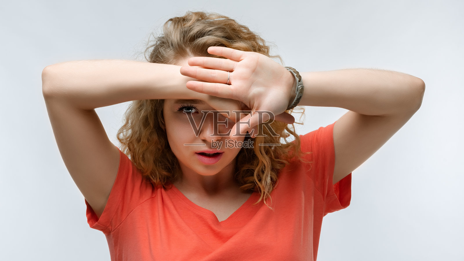 一幅惊恐的年轻女子用手遮住眼睛的肖像。人的情绪、表情概念照片摄影图片