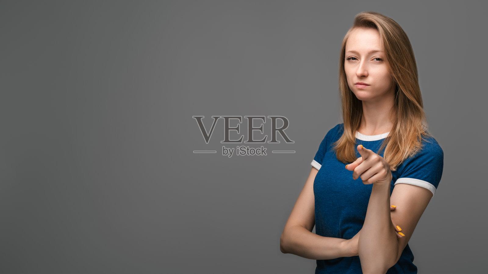 金发直发的女孩不高兴地指着你。孤立的灰色。人的情绪、表情概念。照片摄影图片