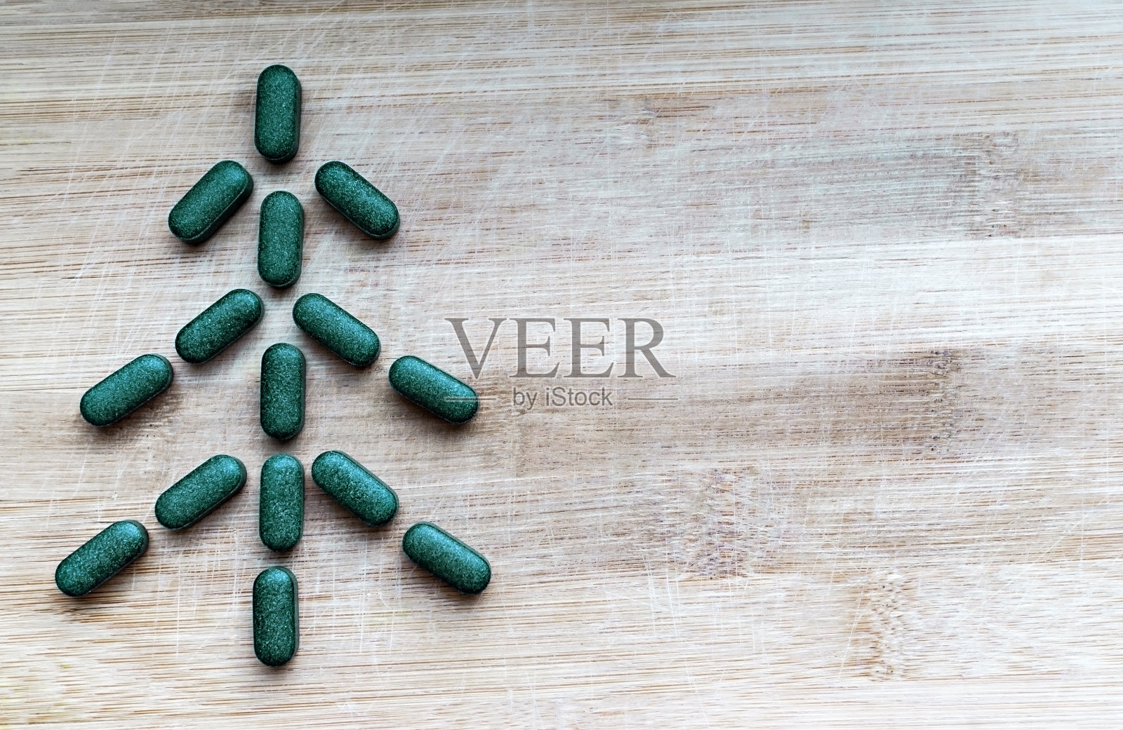 将小球藻、螺旋藻或大麦草做成人字形或圣诞树的丸子放在带有复制空间的浅色木质背景上照片摄影图片