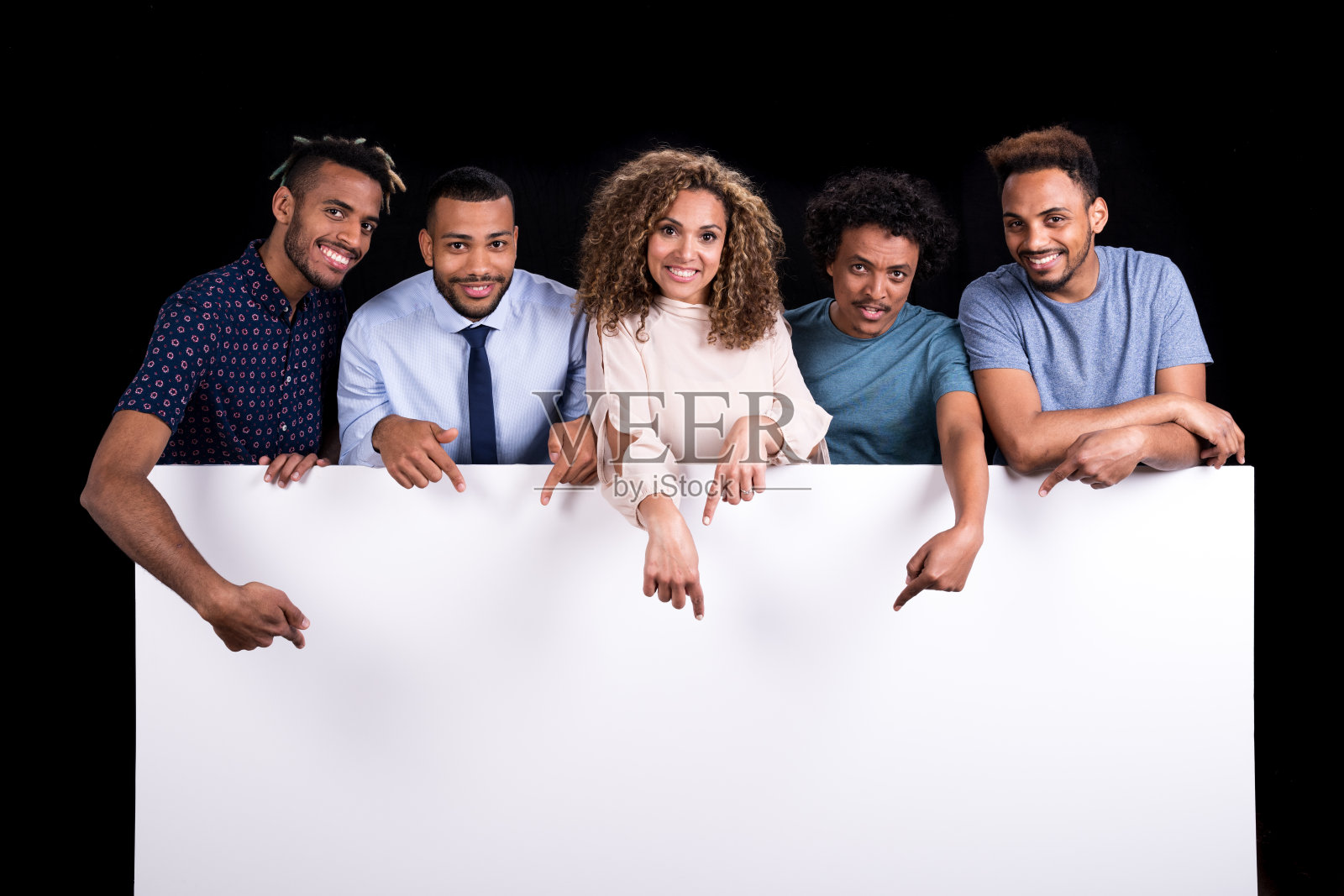 一群微笑的人指着空白的白色桌子为你的文本照片摄影图片