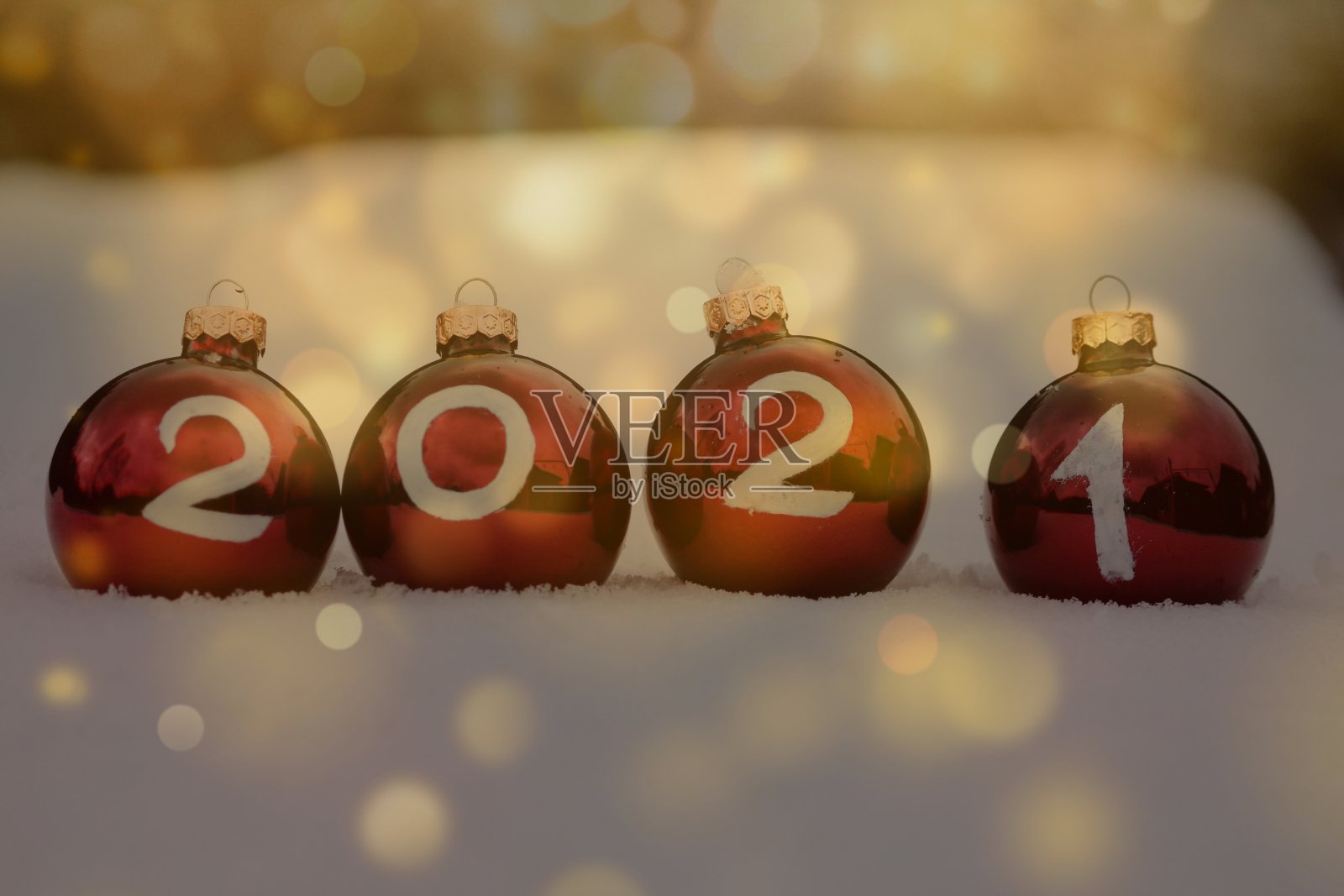 红色勃艮第玻璃圣诞球与2021年的雪在金色的散景。节日的明信片。新年快乐，圣诞快乐。照片摄影图片