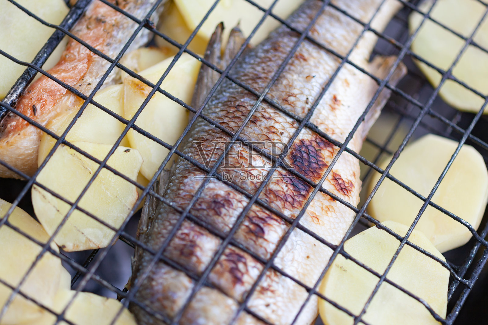 炸鲈鱼配土豆放在烤架上照片摄影图片