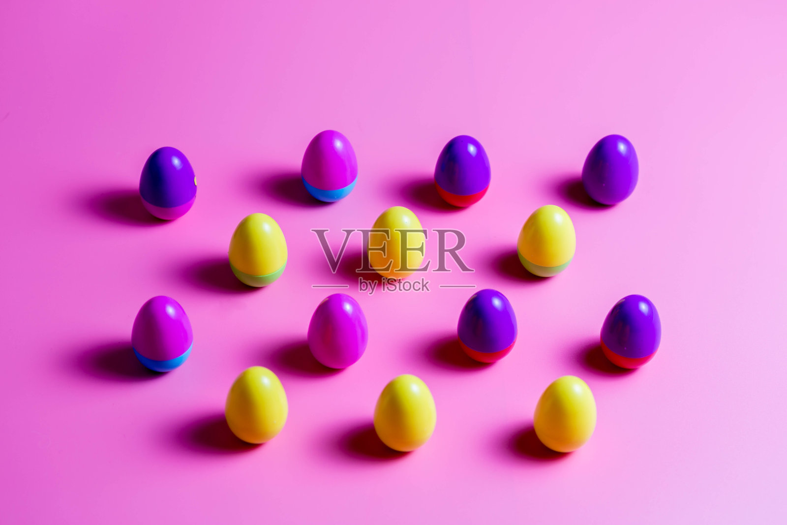 粉红色背景上的彩色塑料复活节彩蛋。照片摄影图片