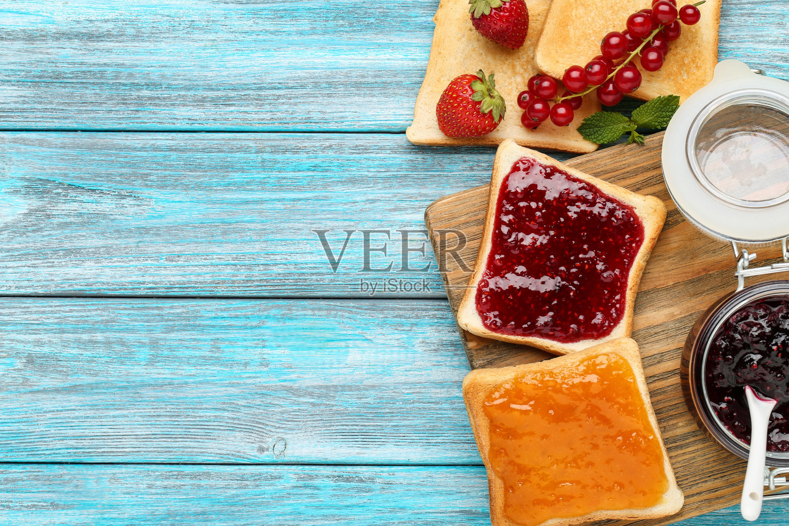 蓝色的木桌上放着覆盆子和杏酱照片摄影图片